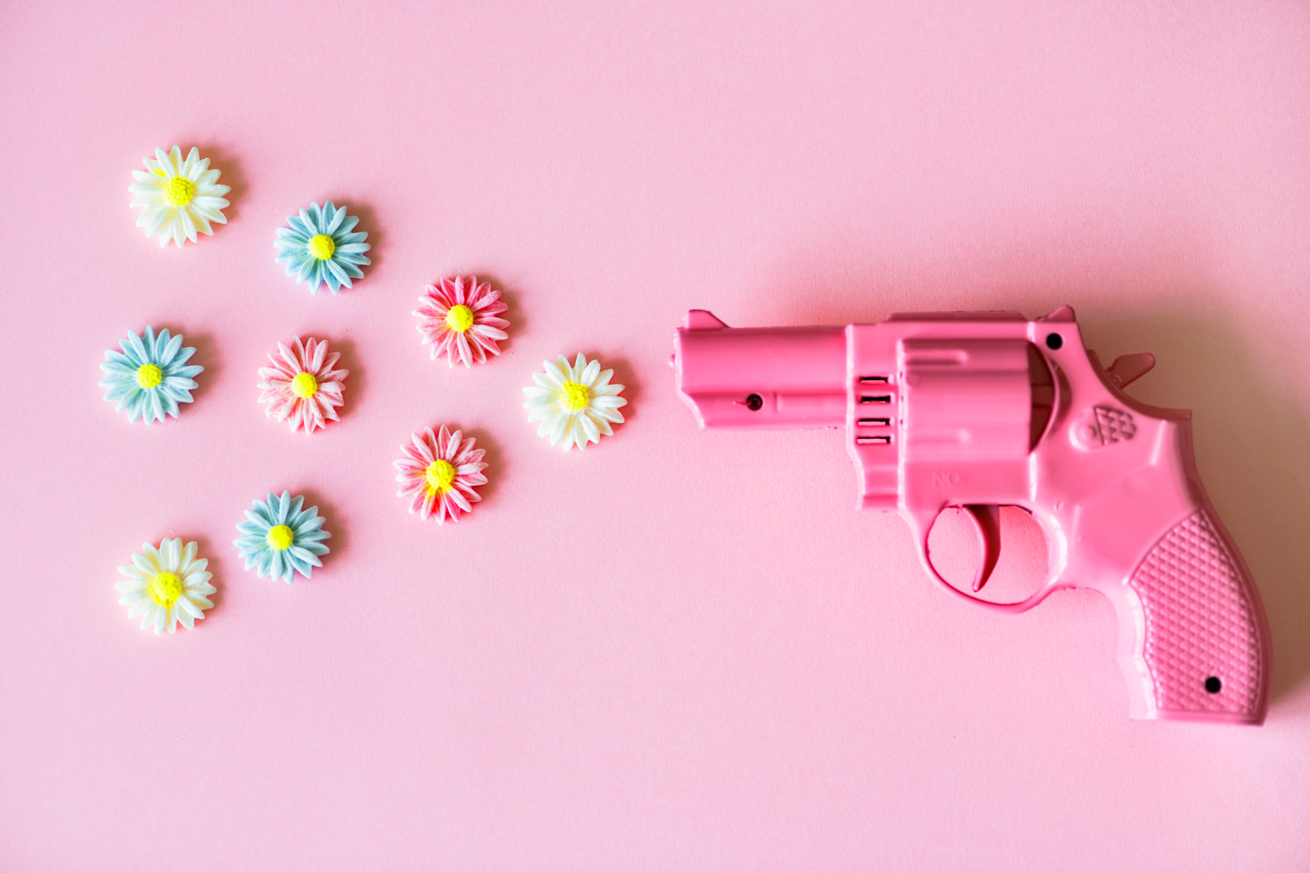 an arrangement of pink and blue flowers and a pink toy gun