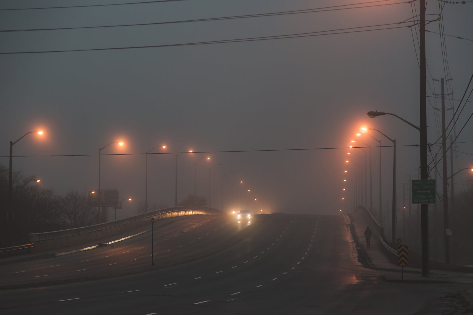 a street at night with light poles in the distance and fog