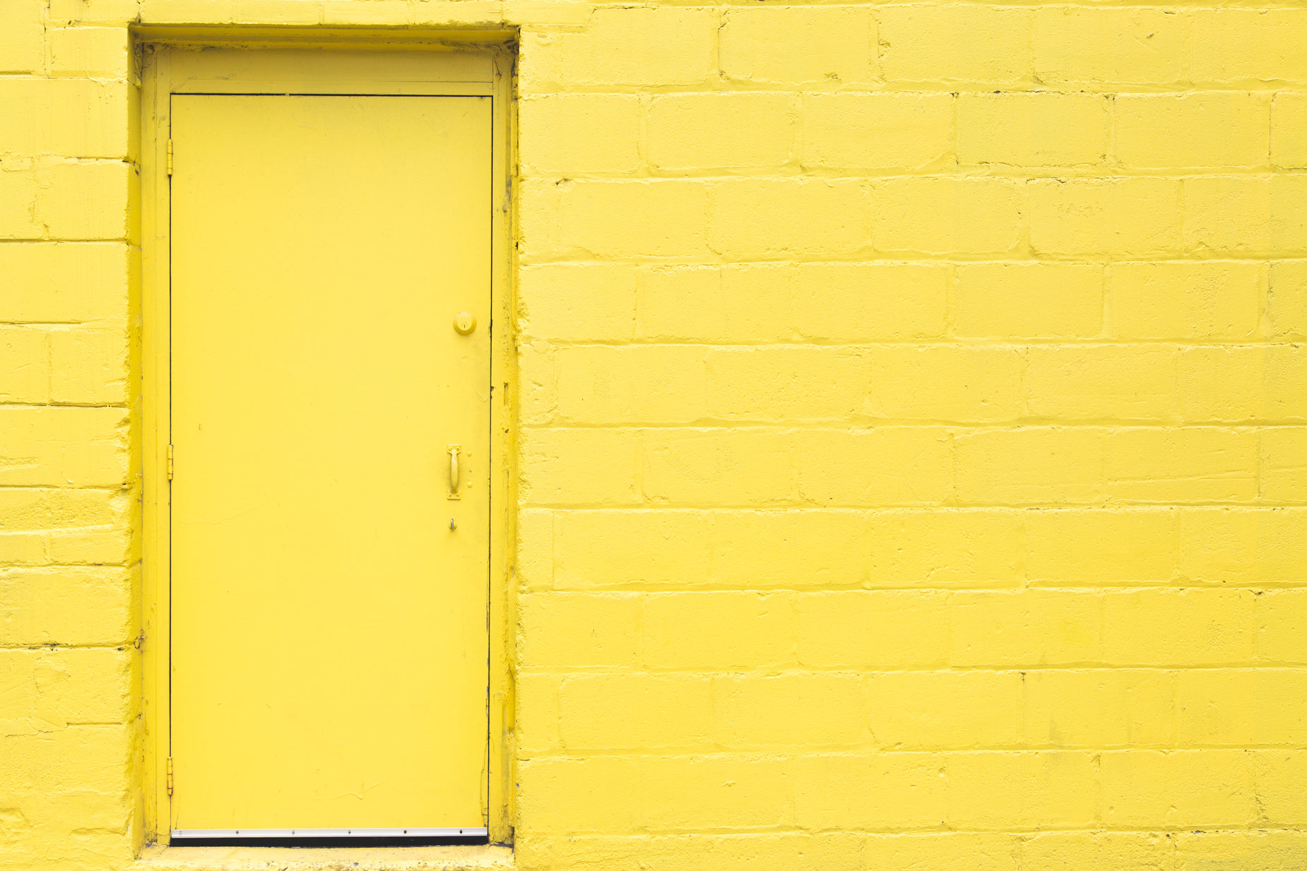the door is yellow near a brick wall
