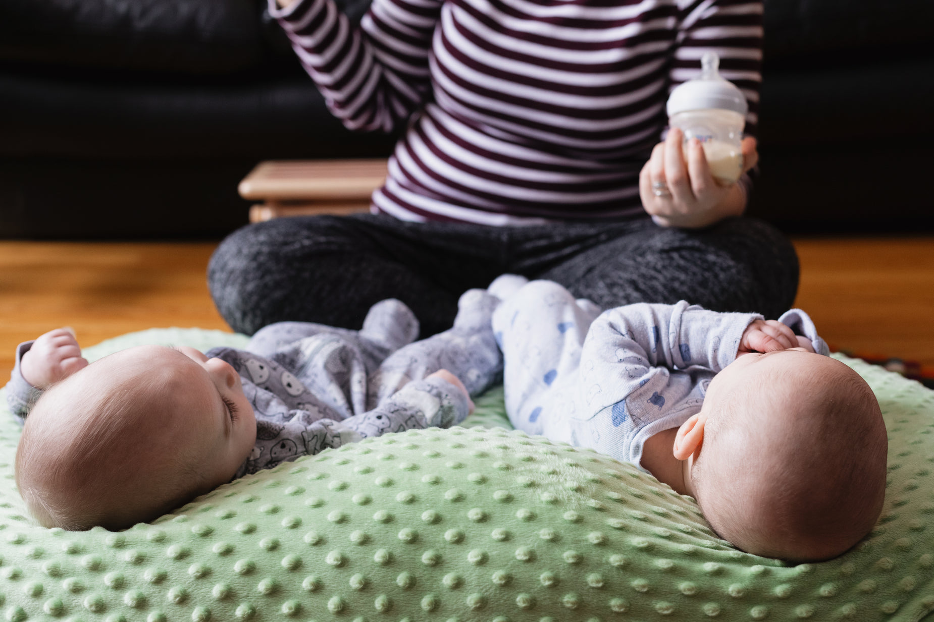 babys are lying down with their mother eating food