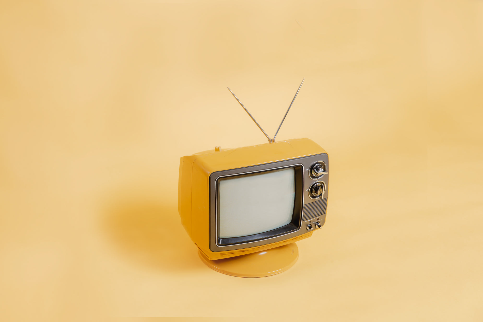 a old television is on top of a yellow wall