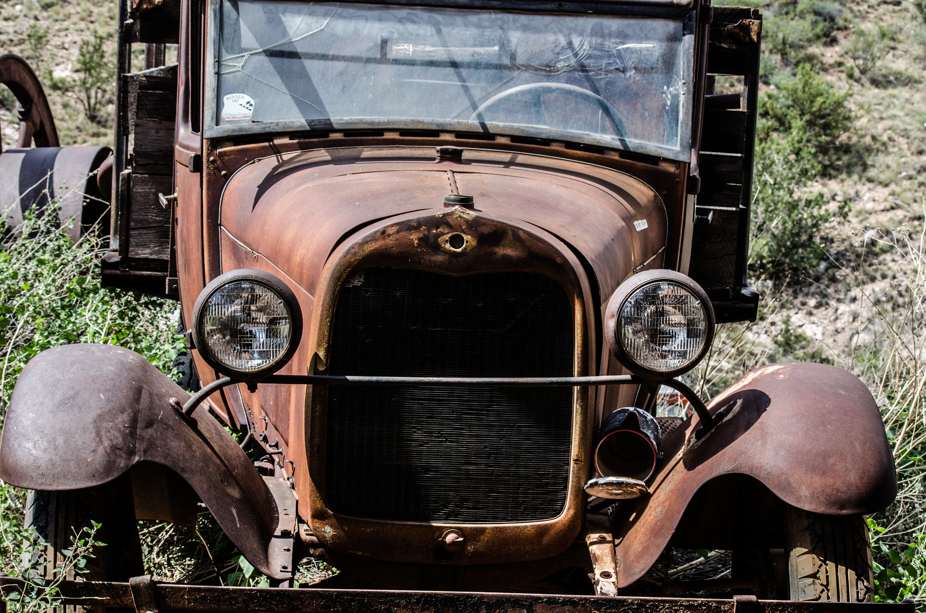 an old rusted out truck in grassy field