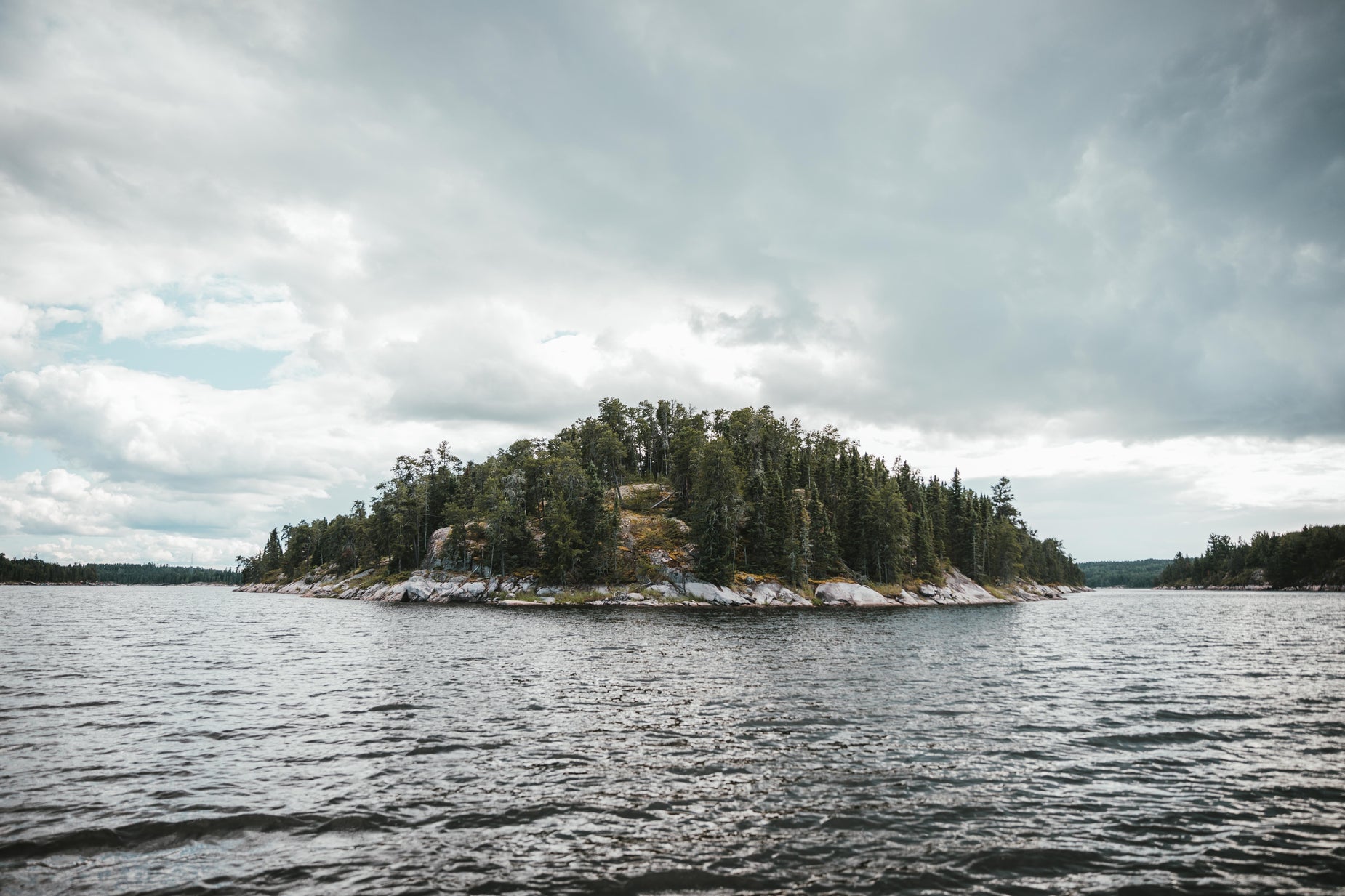 an island surrounded by large trees in the middle of the ocean