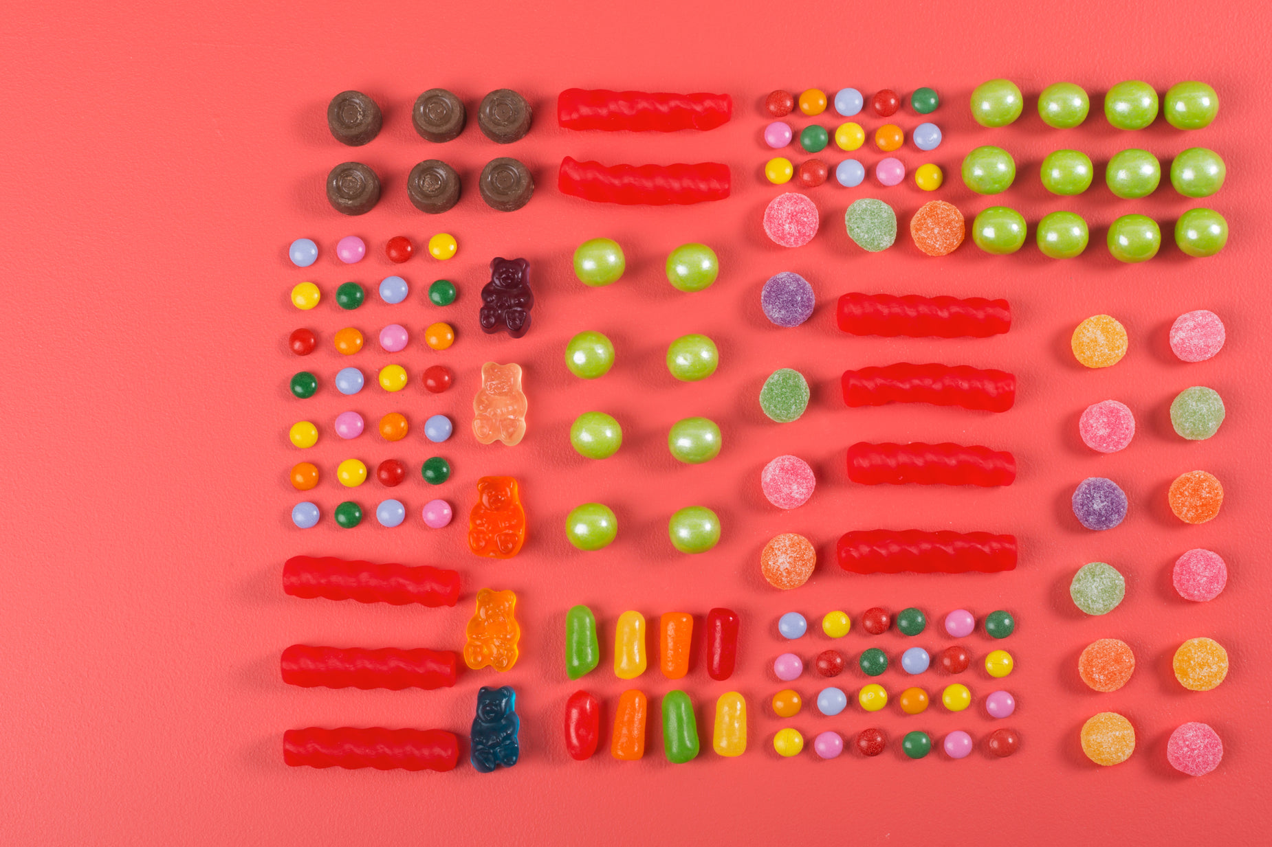 a variety of candys and candies spread out on a bright pink background