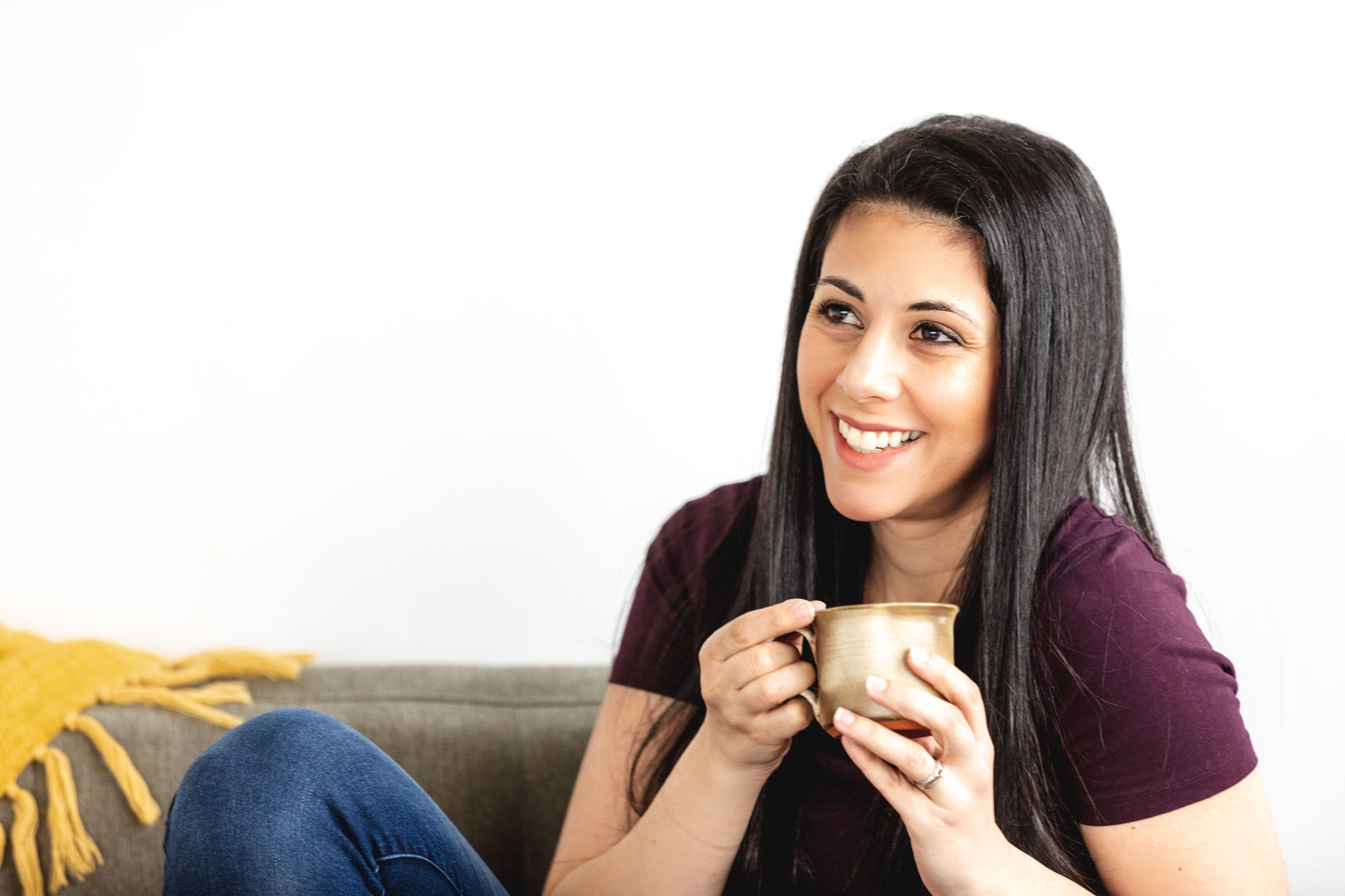a woman sitting on a couch while holding a cup