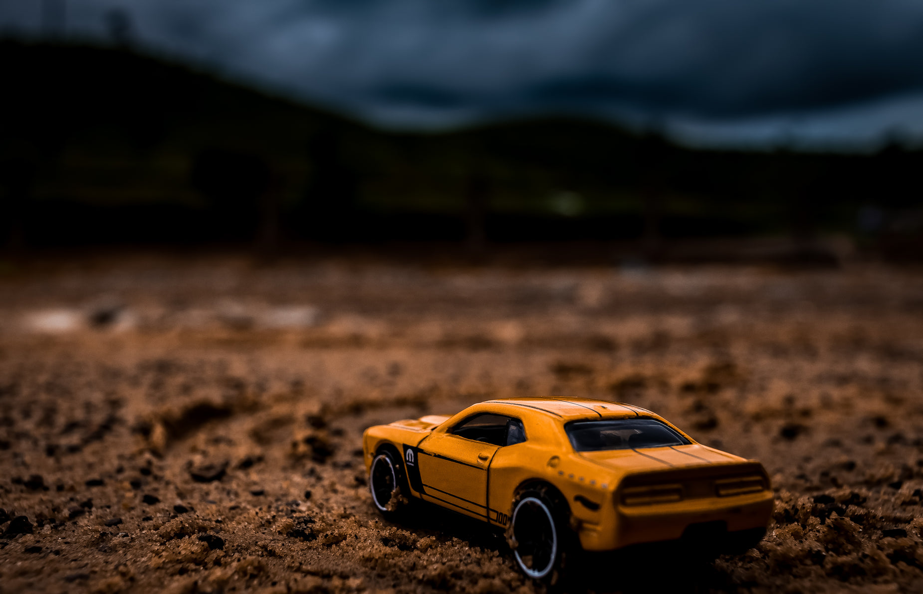 toy car parked on muddy ground in dark field