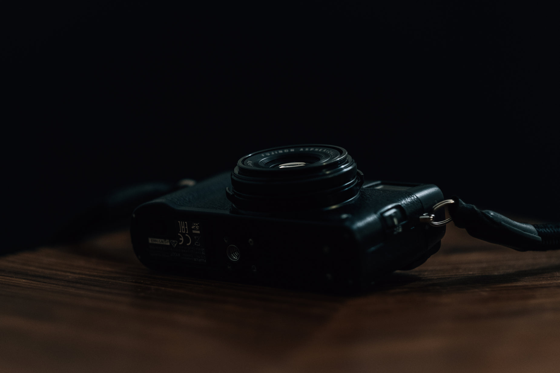 a camera with a black lens sitting on a wooden surface