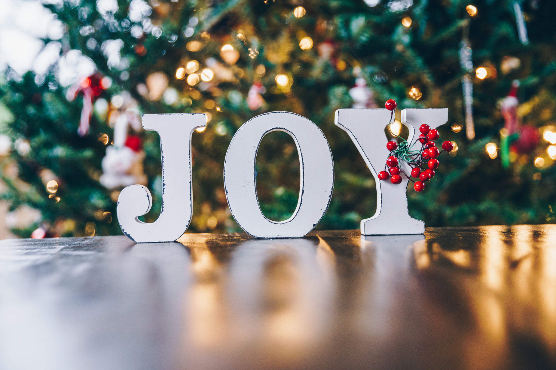 a white sign reading joy next to christmas tree