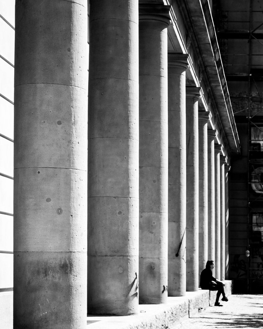 a person is sitting in the shade of four columns