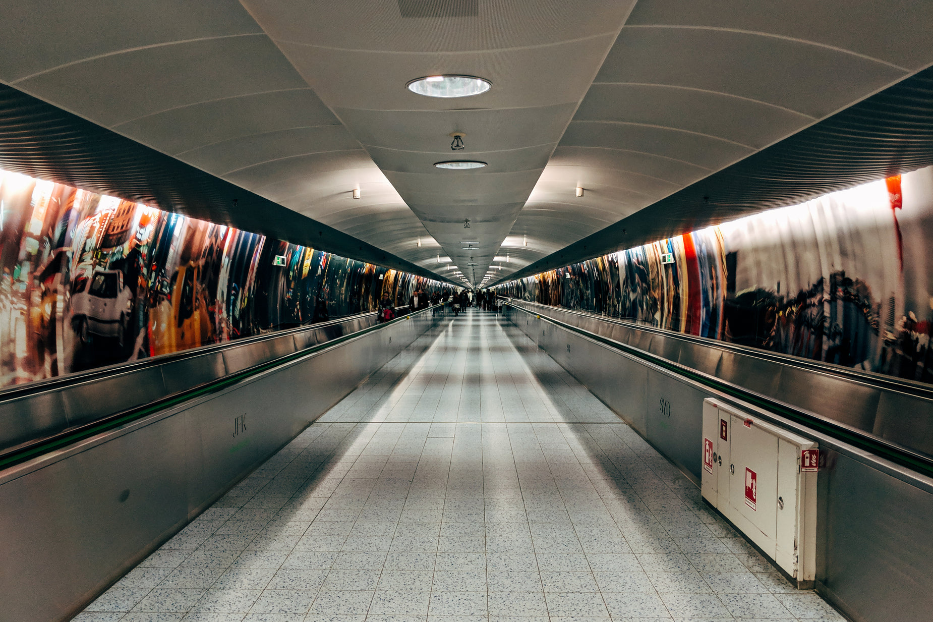 an empty long silver colored hallway with people walking