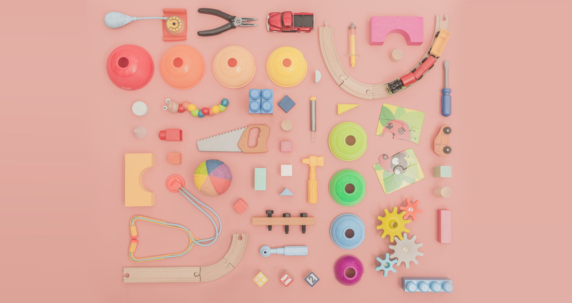 various wooden toys and supplies are laid out on a pink background
