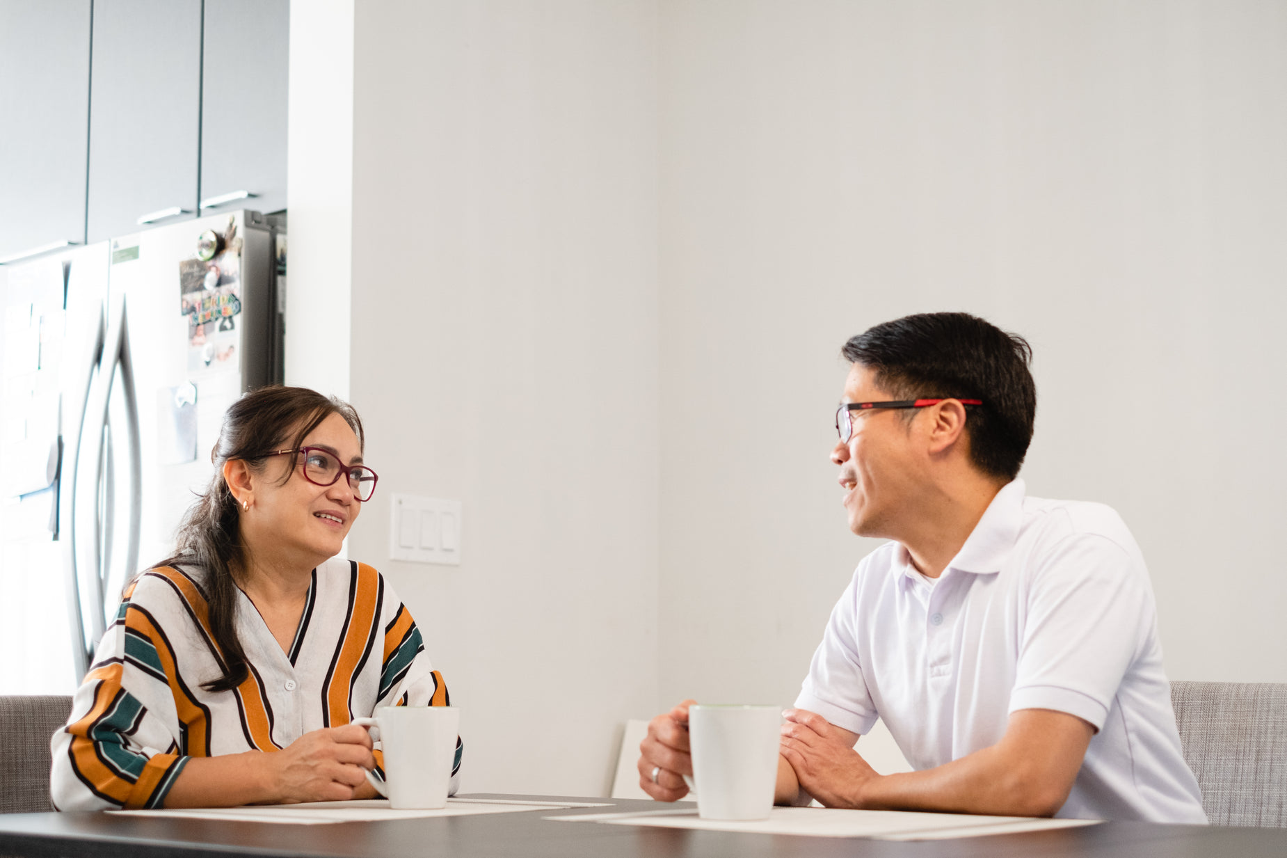 two people sitting at a table talking and drinking