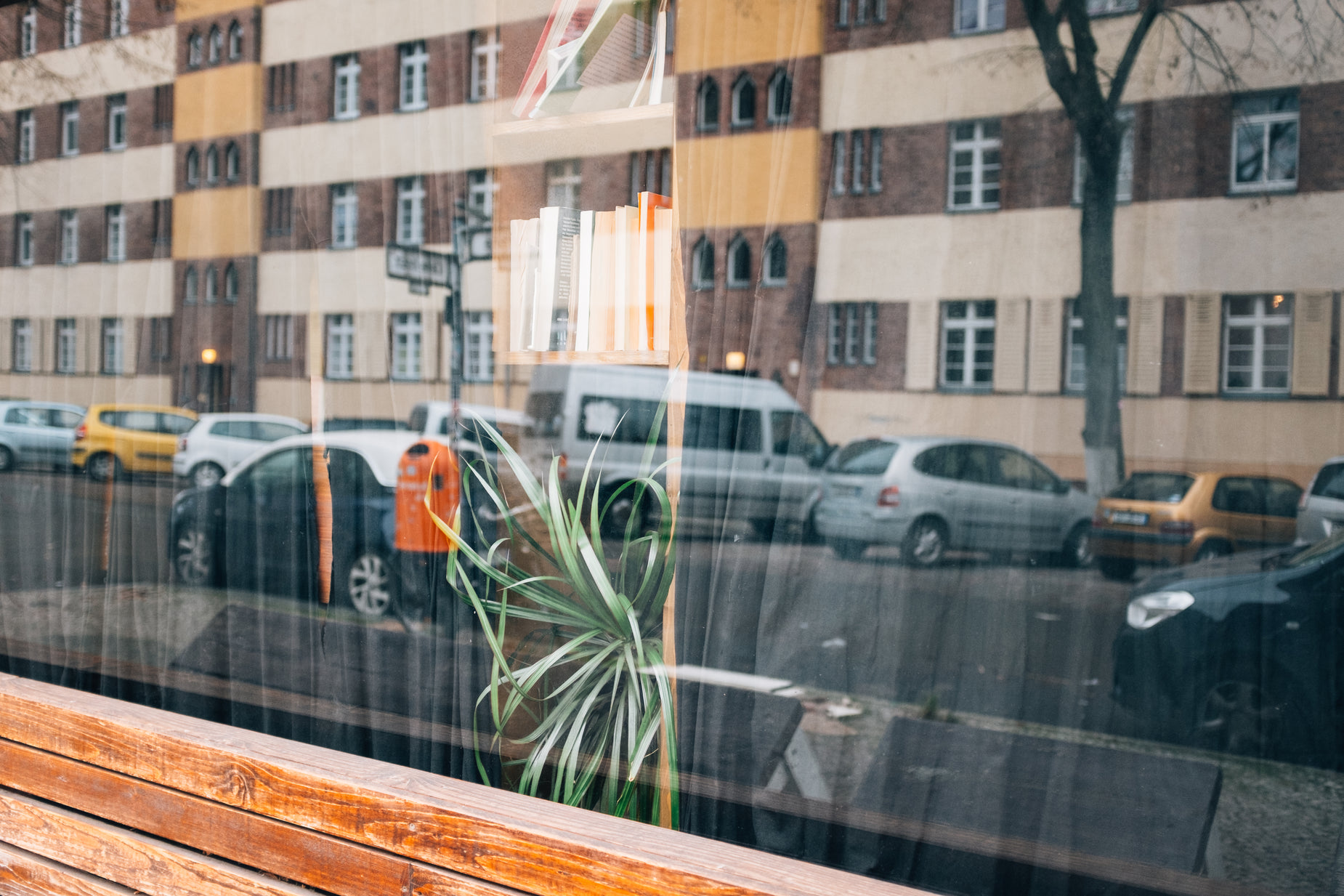 a car sits parked on the street in front of a building and a plant is in the window