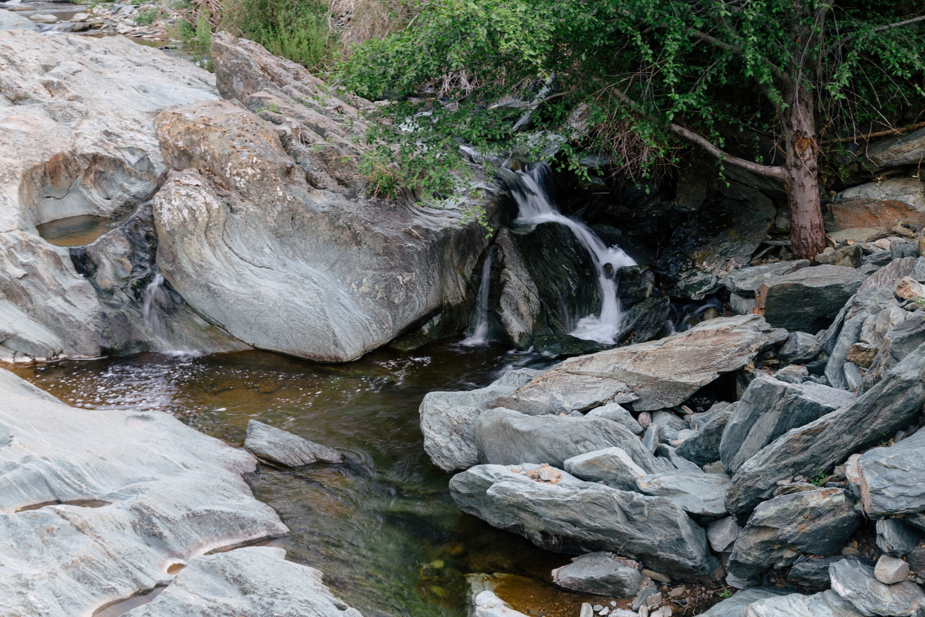 a stream flowing from a rocky river bed with lots of boulders