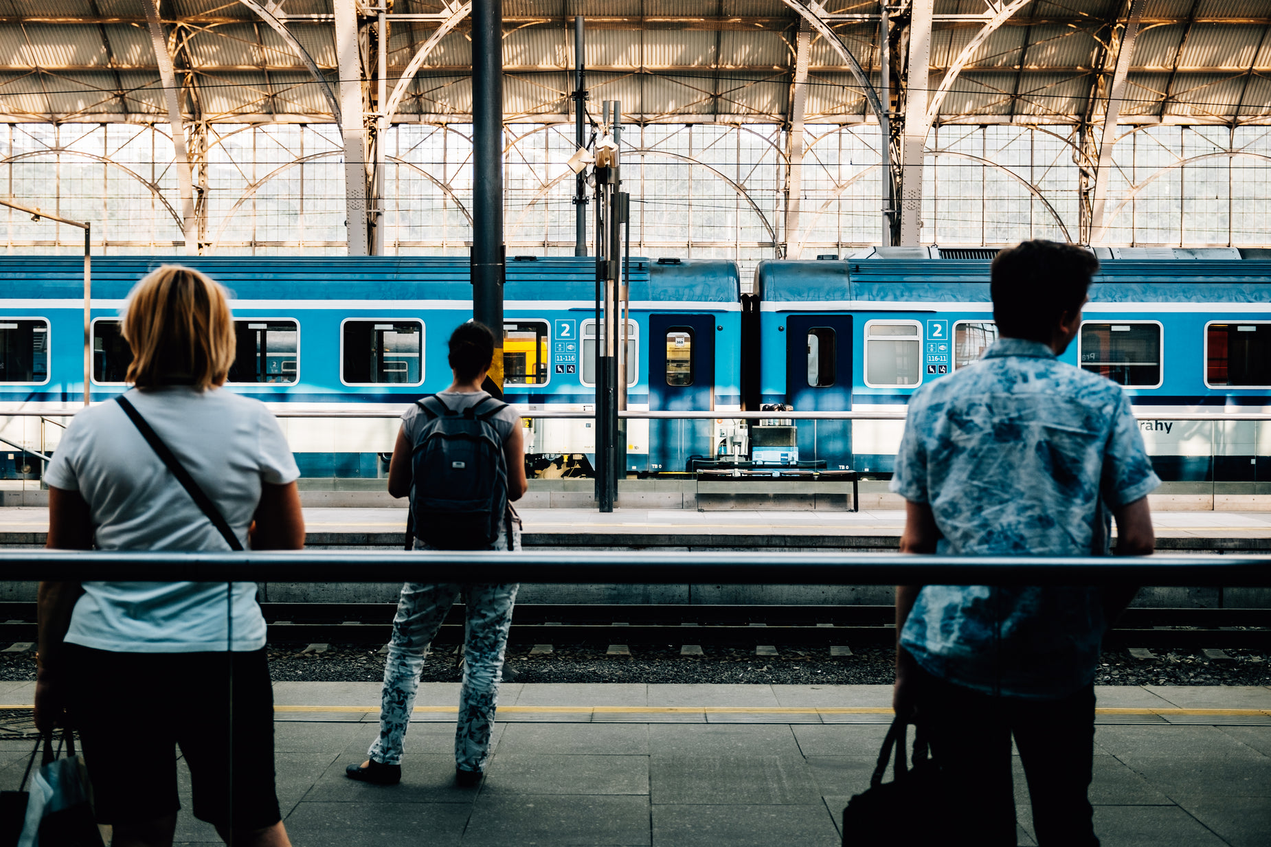 three people looking at a train while standing on a platform