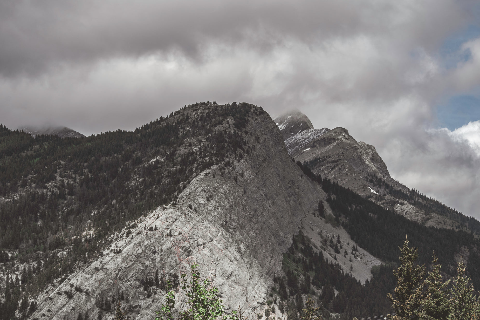 a mountain scene with trees and a cloudy sky