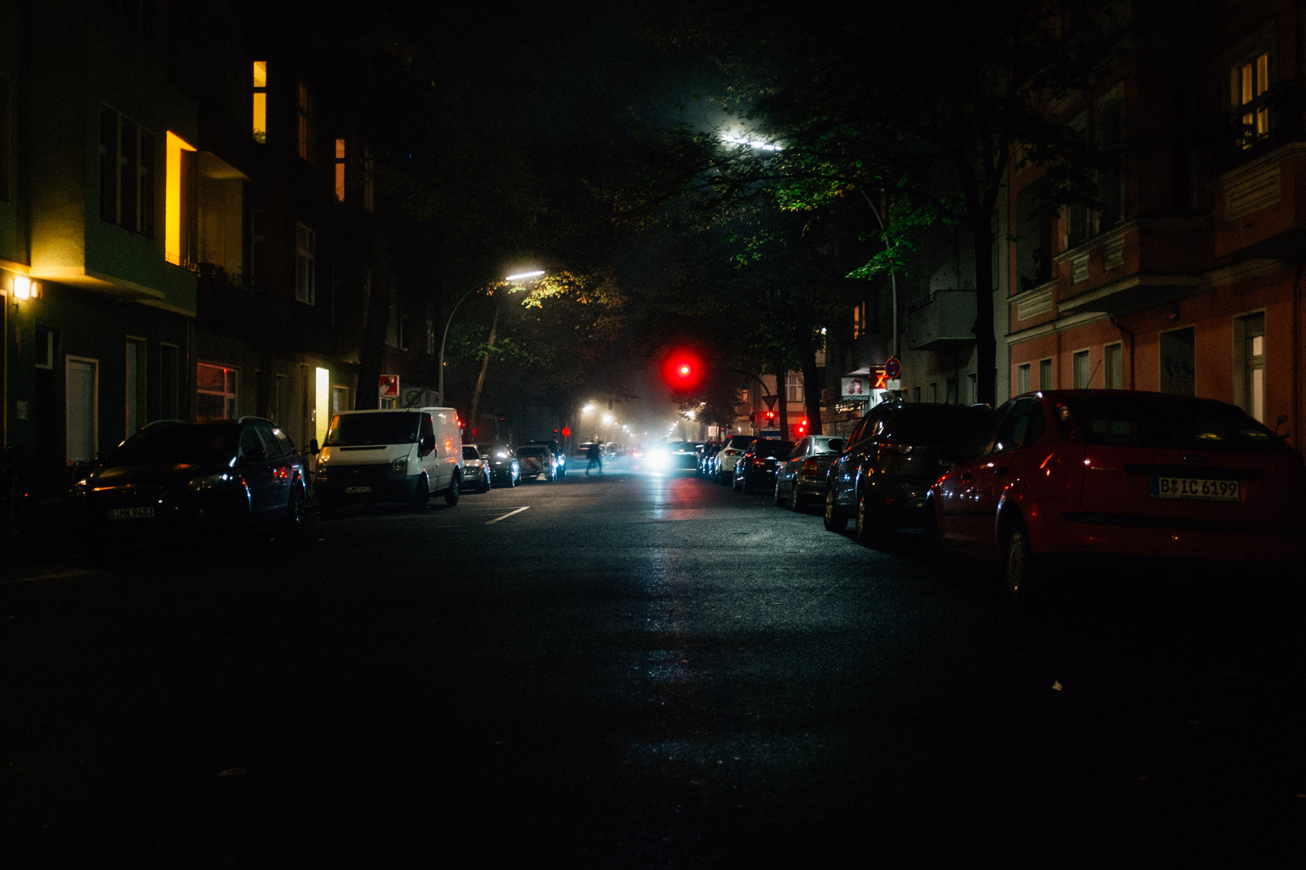 a red light shines brightly as cars and trucks travel down the street