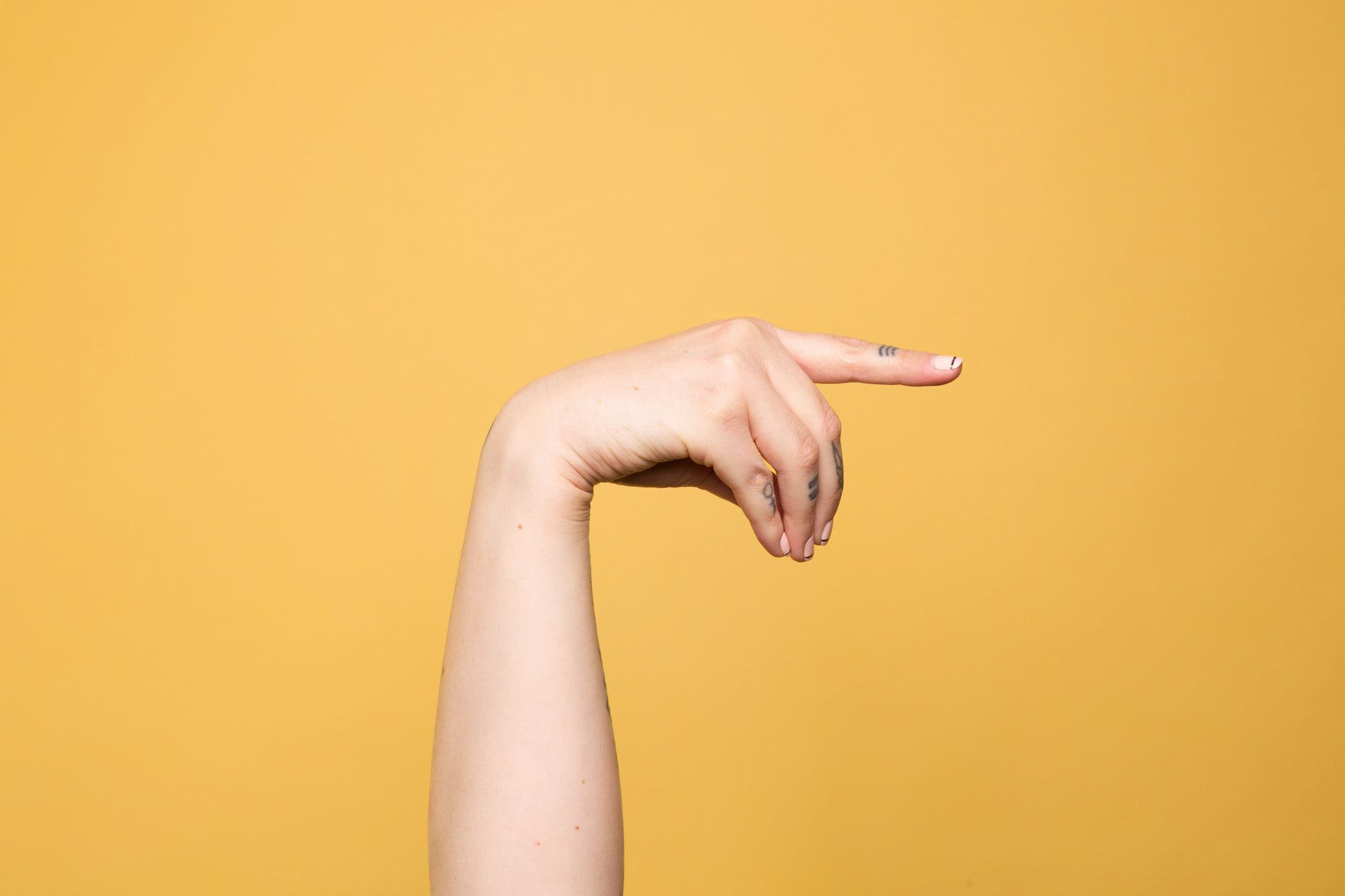 a woman's arm reaching out towards soing with one hand and her other thumb extended forward, against an orange background