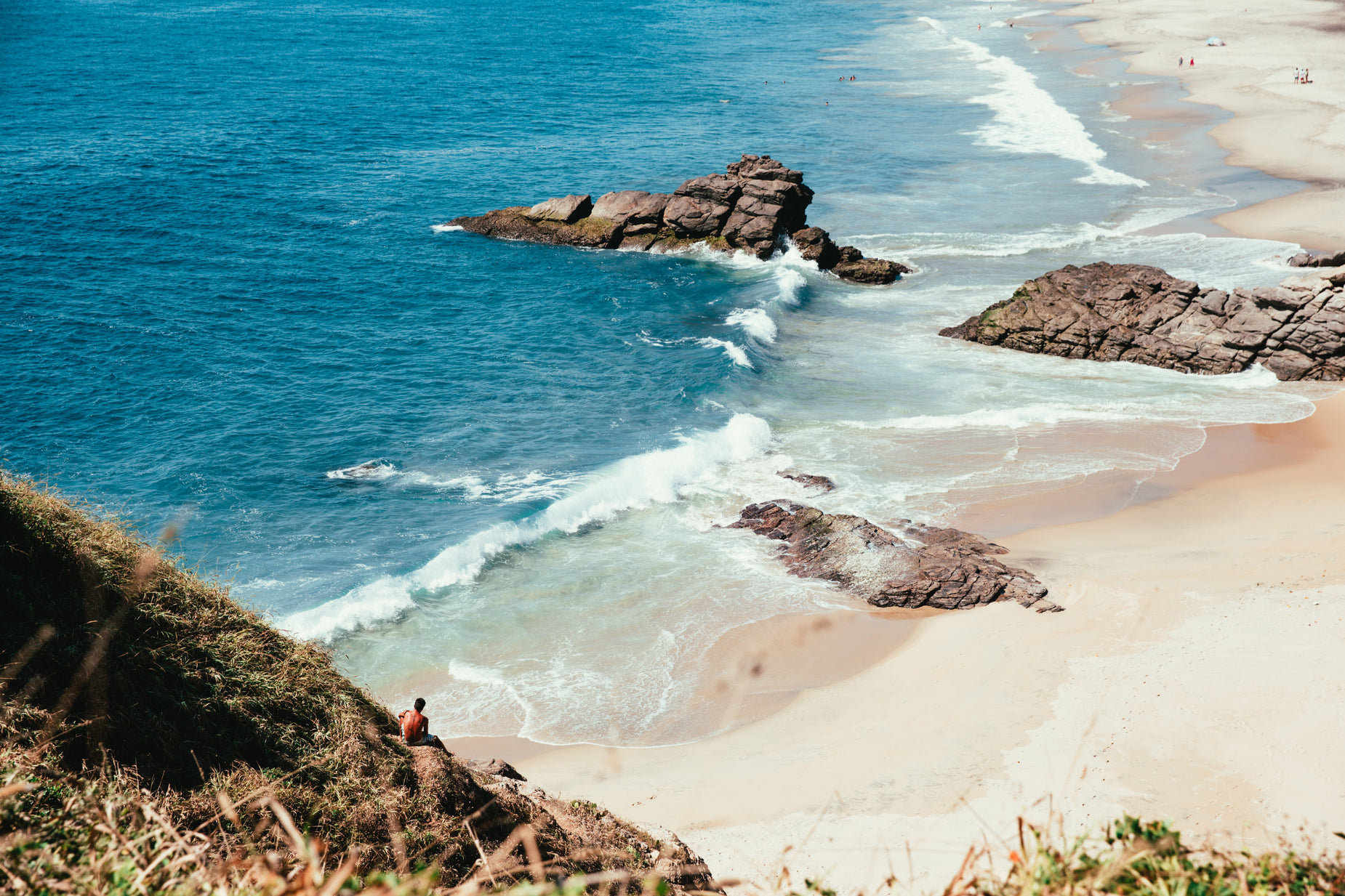 two people are standing on the rocks of a cliff by the ocean