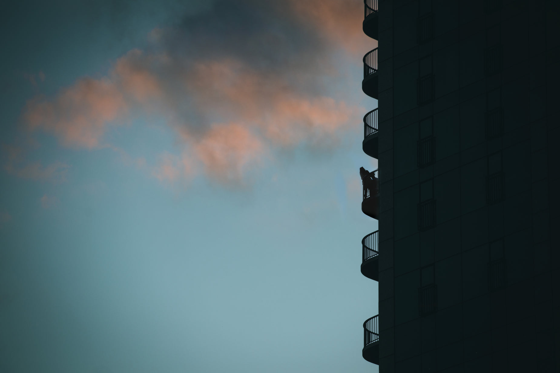 pink clouds hover behind an apartment building