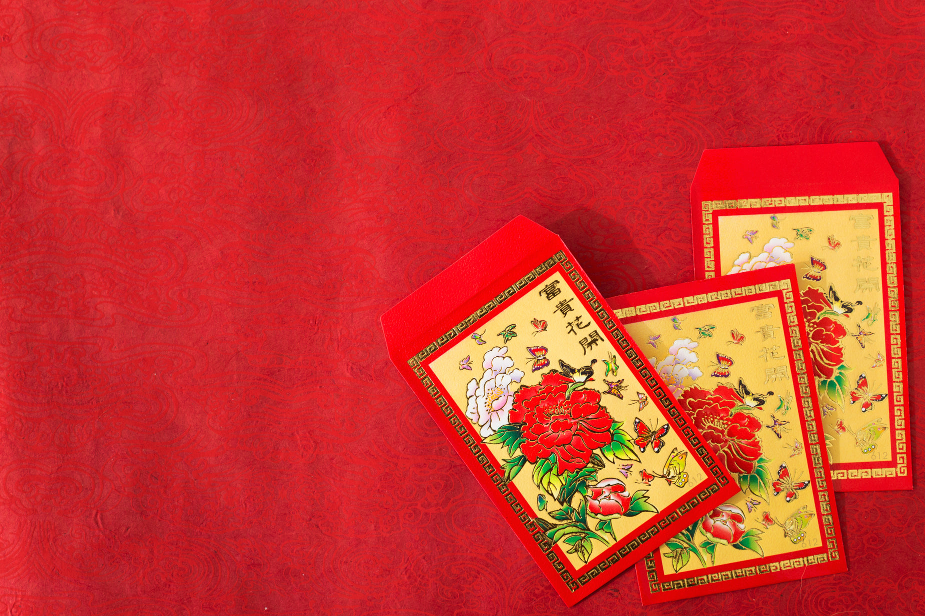 three red envelopes that are in the shape of flowers on a red background