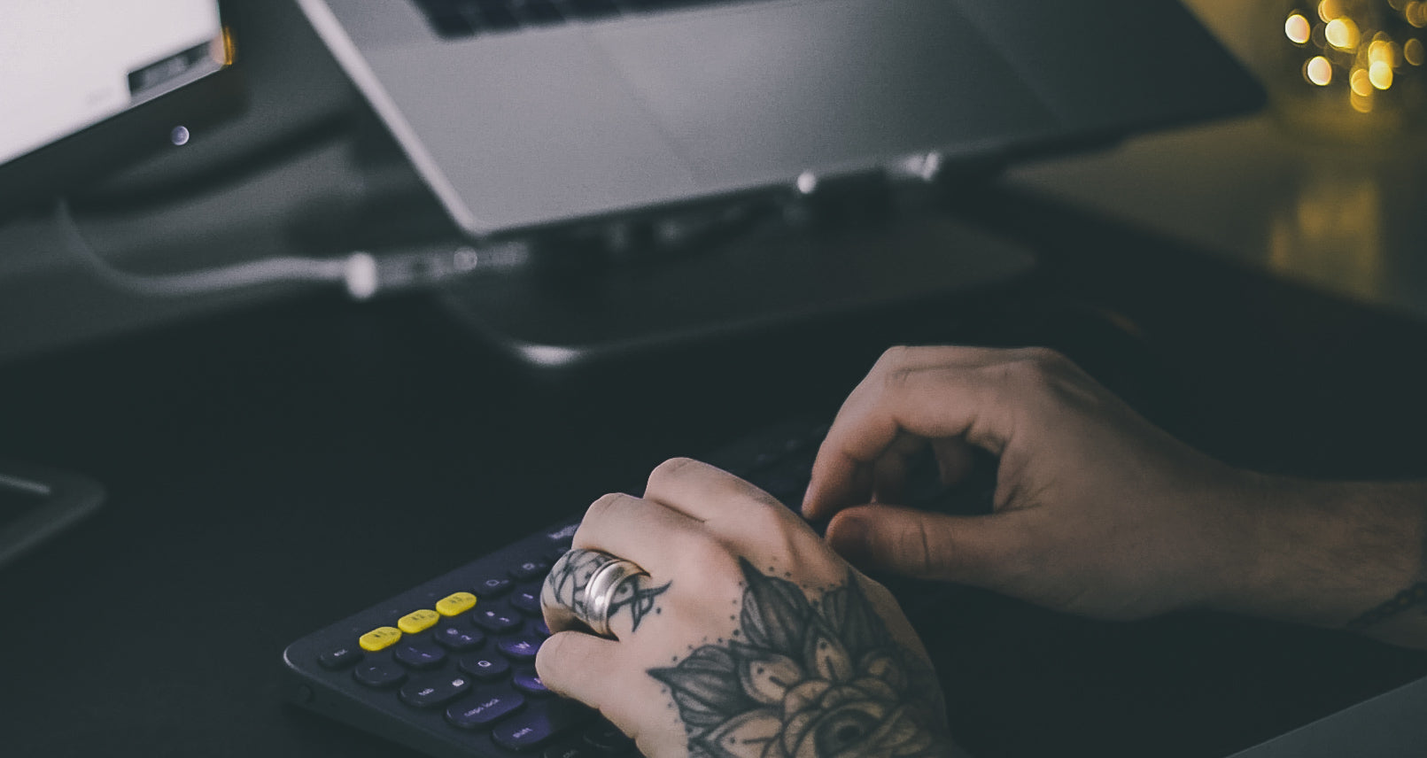 a tattooed man typing on a black keyboard