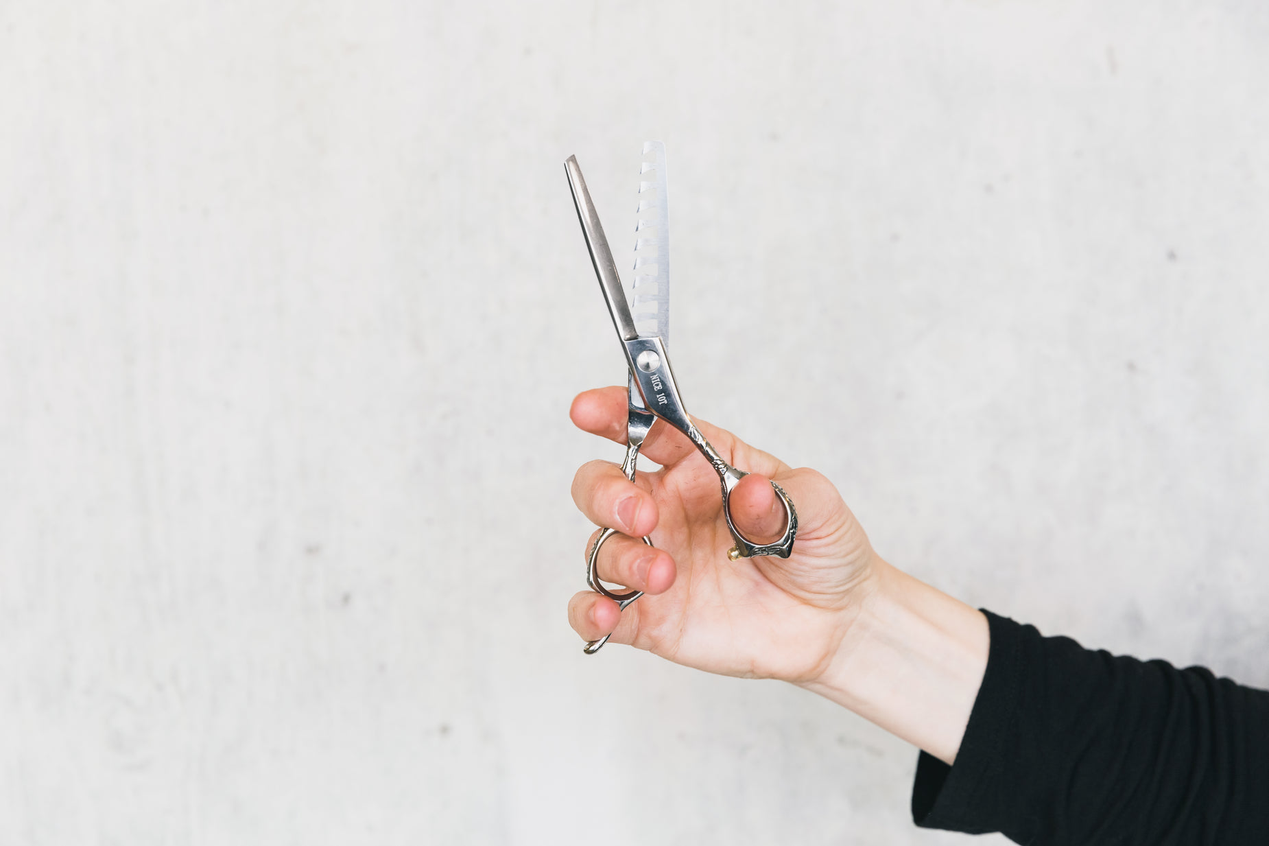 a person holding out scissors on top of a white wall