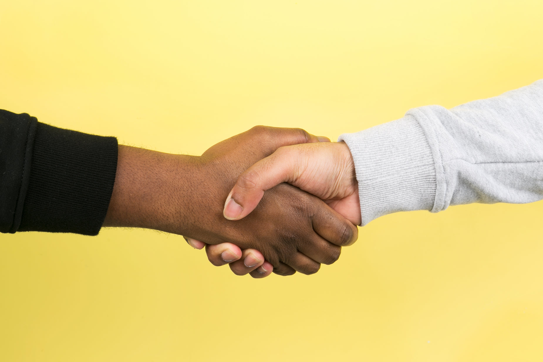 two men shaking hands on a yellow background