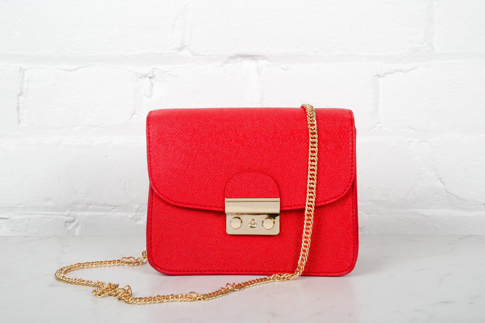 a red purse with golden hardware on a chain