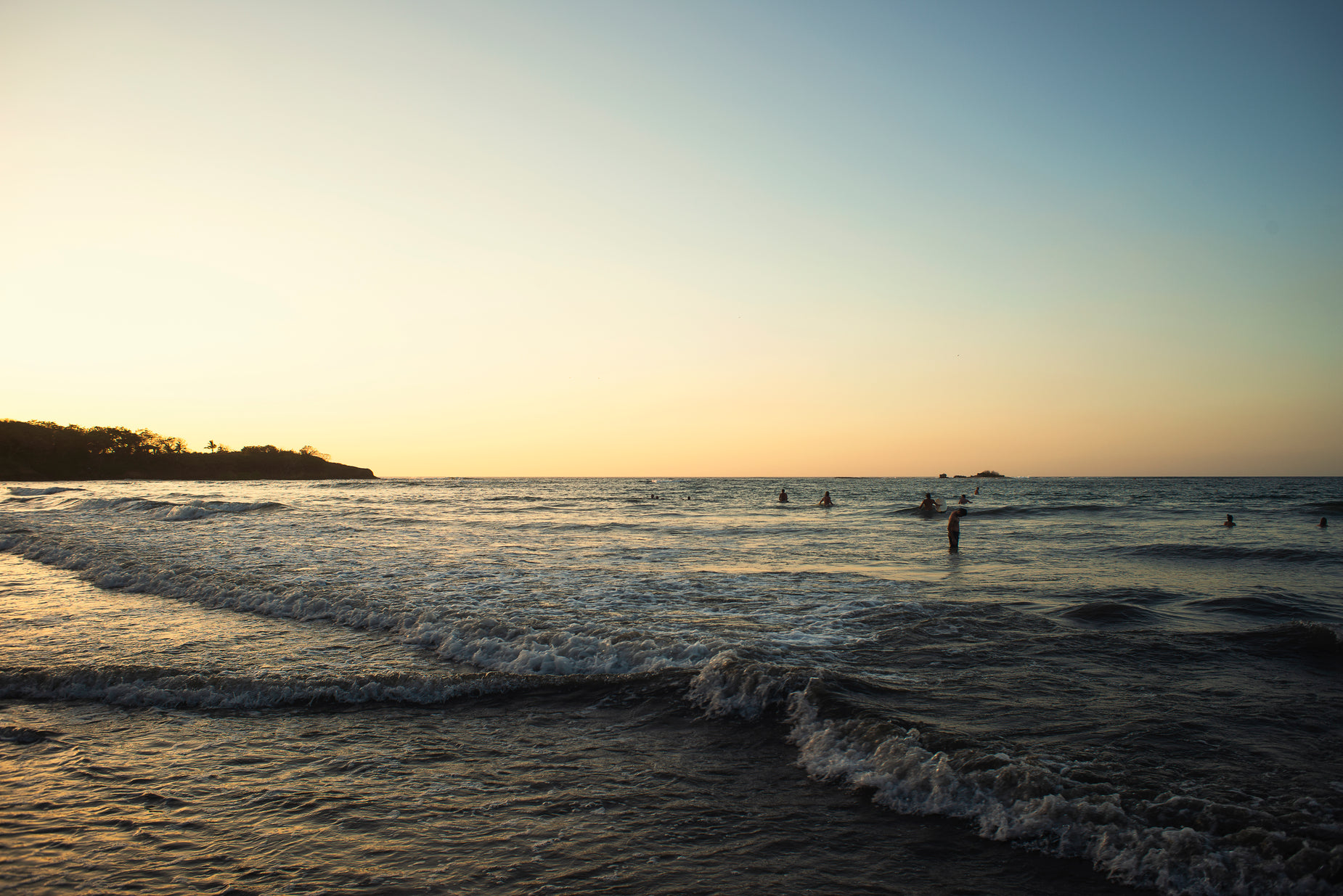 people are swimming in the ocean on a sunset