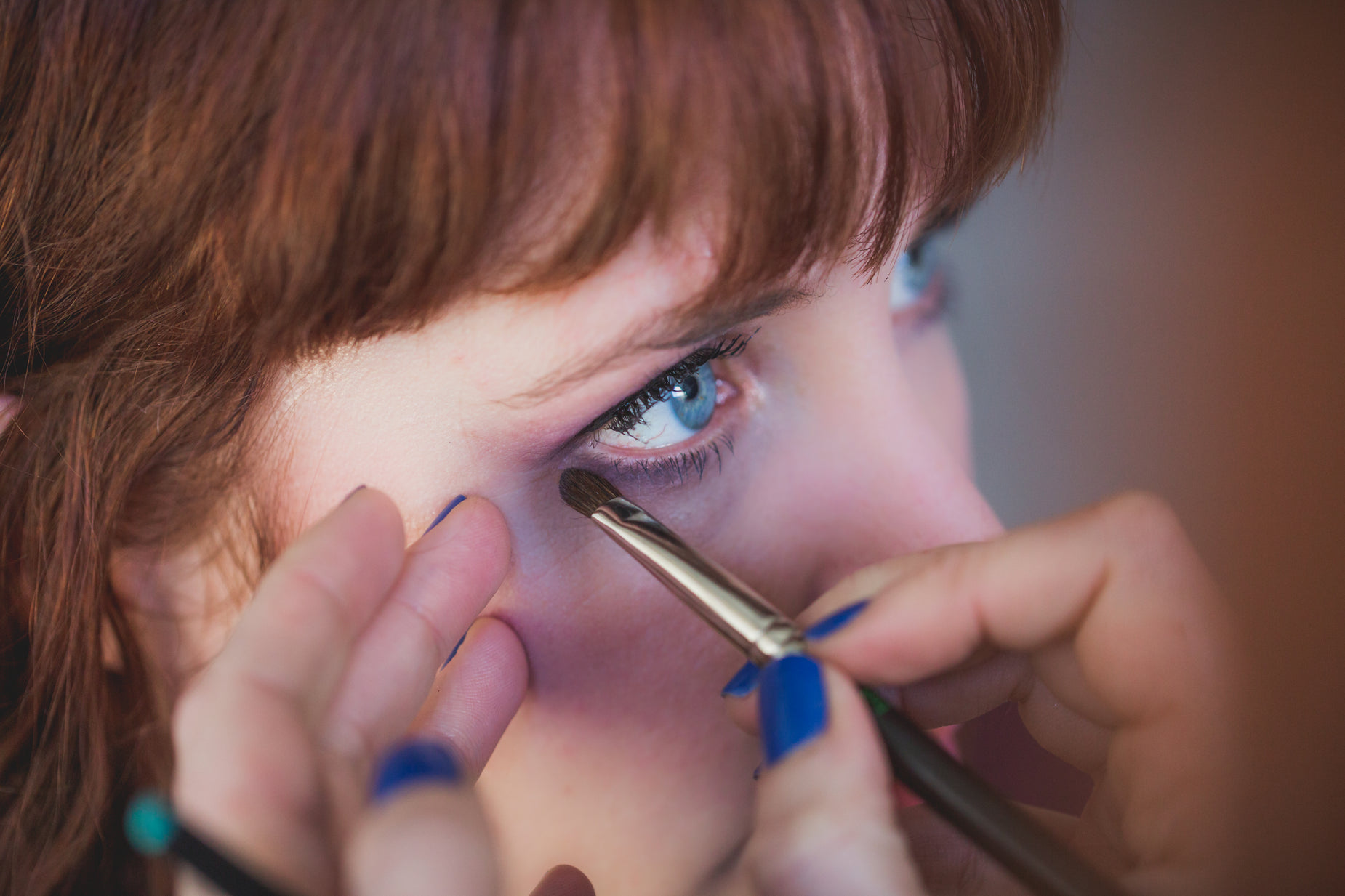 a woman using makeup brushes on her eye