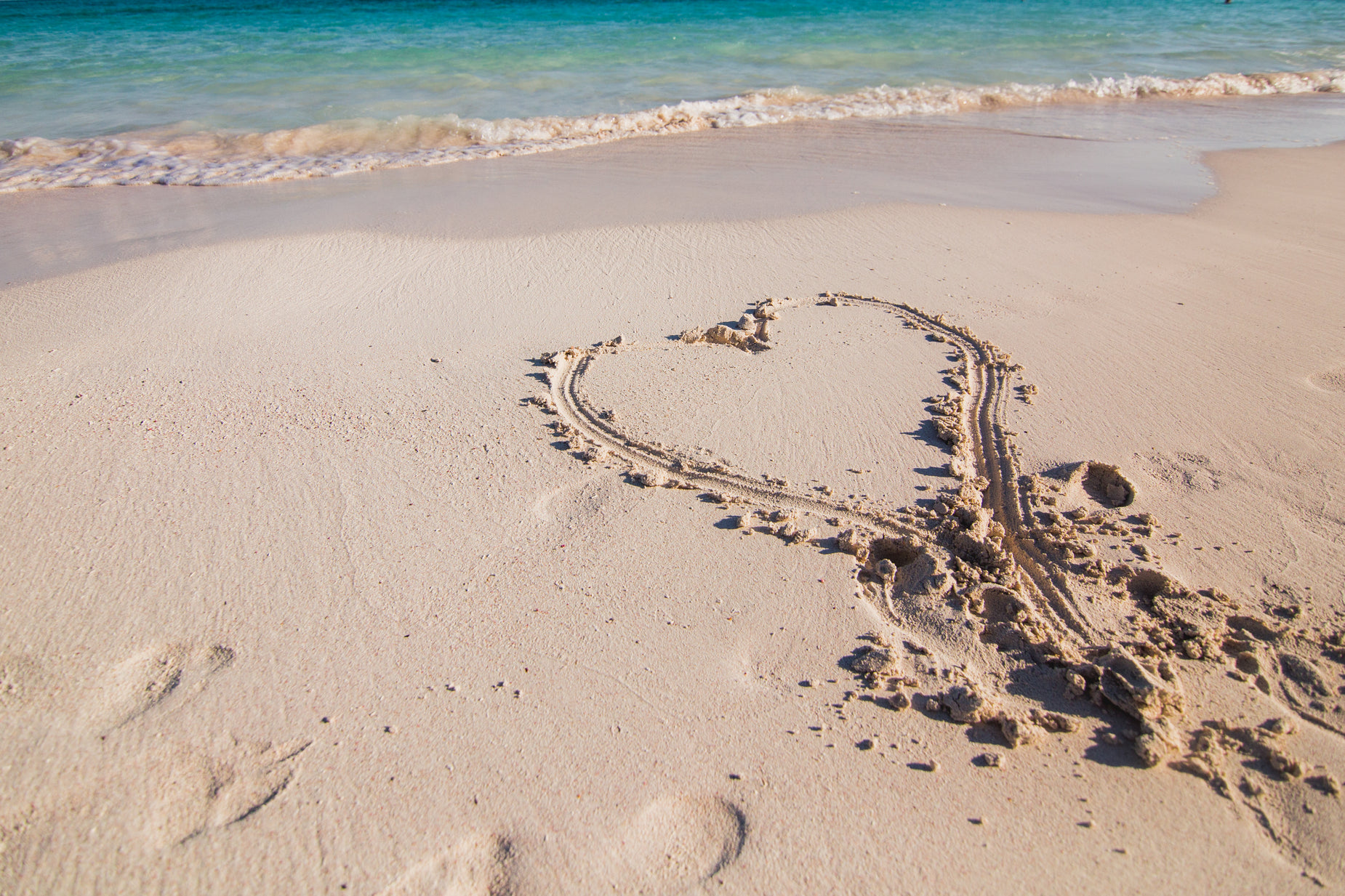 the heart is drawn on the beach by hand
