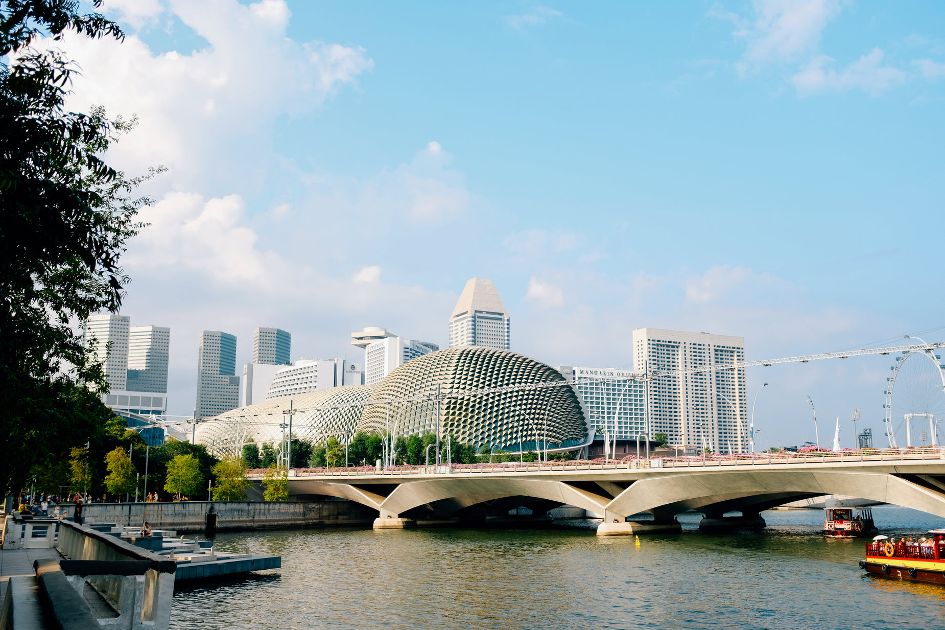 a boat traveling down a river underneath a tall building