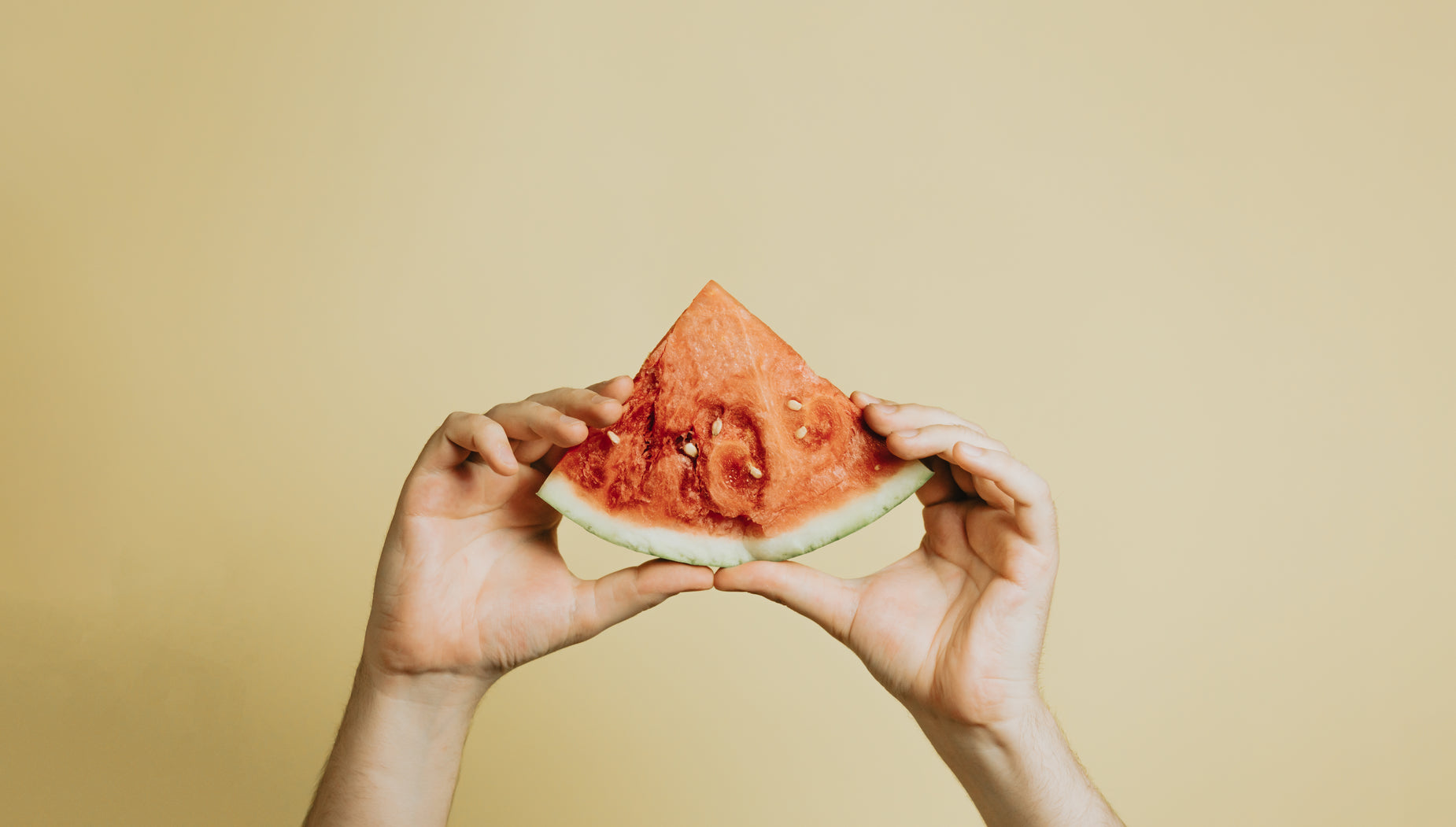 a person holding a slice of watermelon over their face