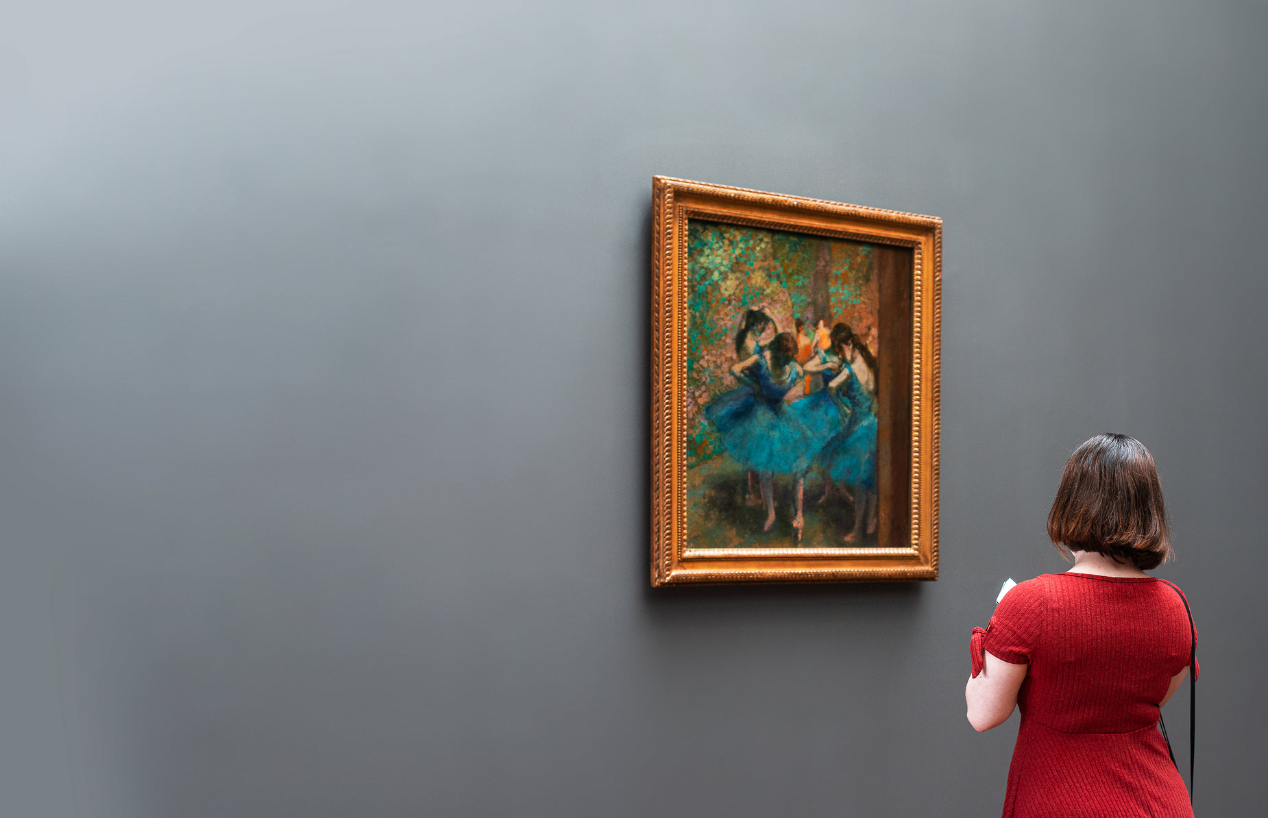 a woman in a red dress looking at a painting