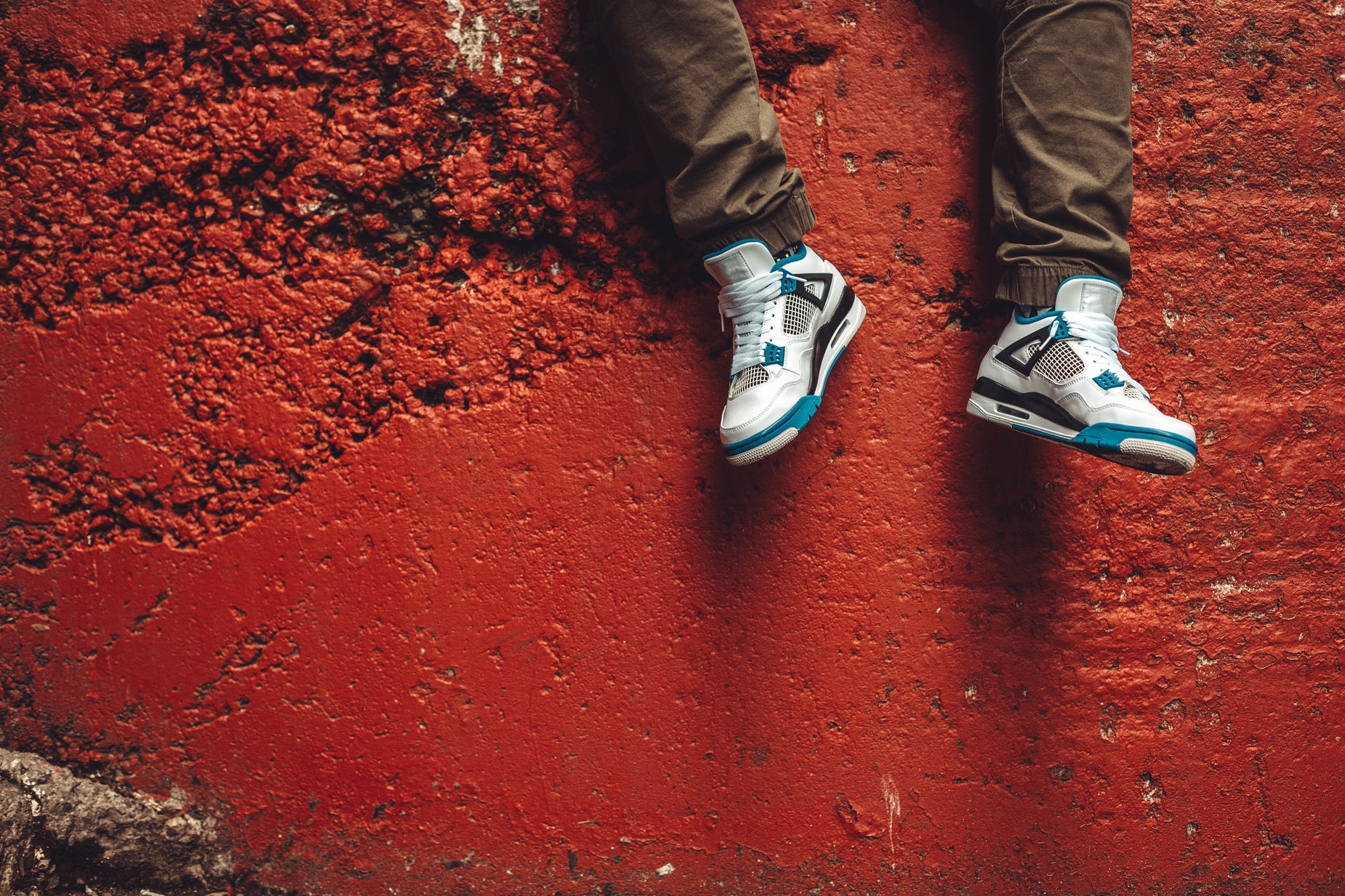 person wearing white adidas shoes standing on a sidewalk