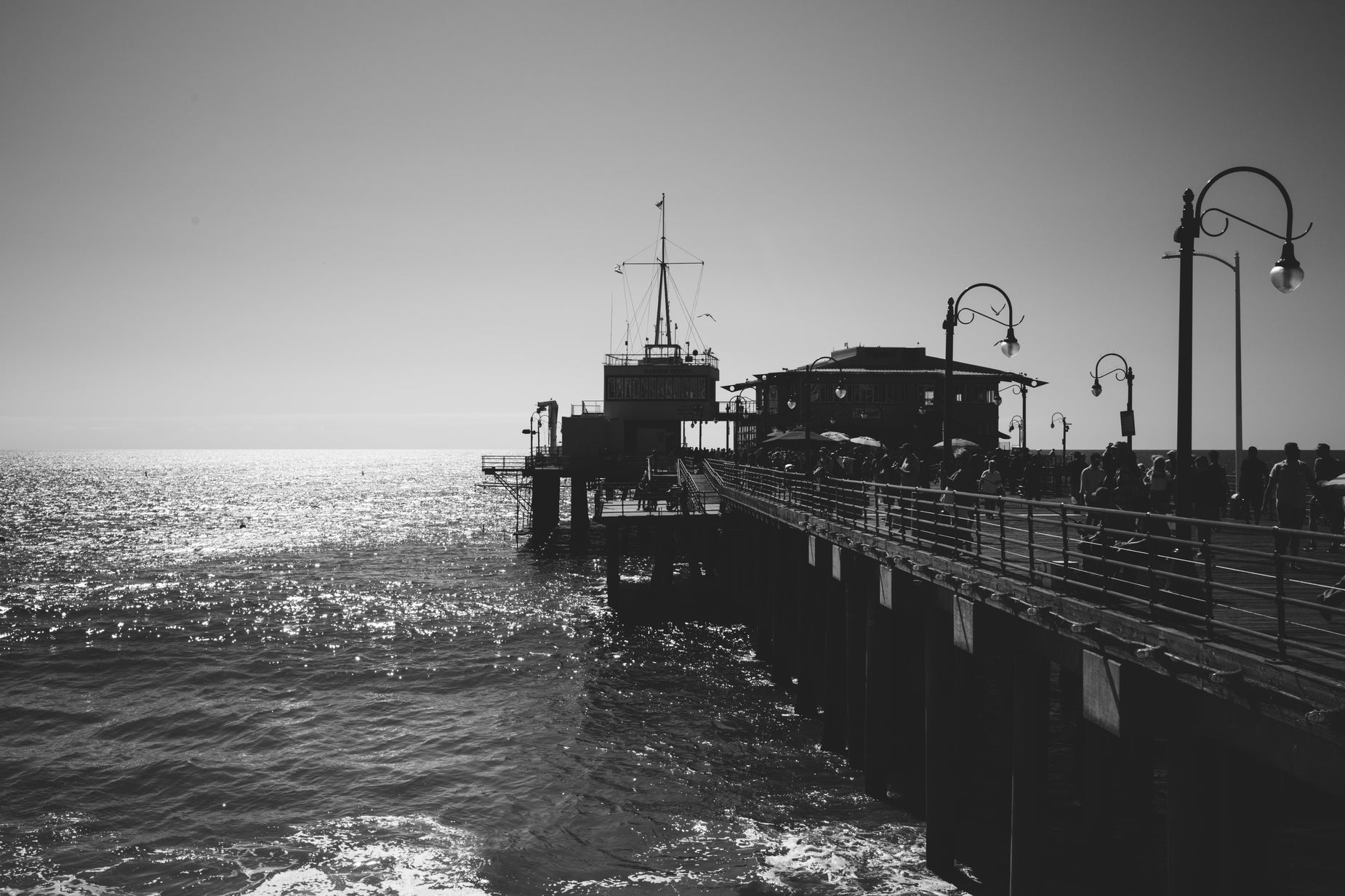 people enjoying the sun next to the pier on an ocean