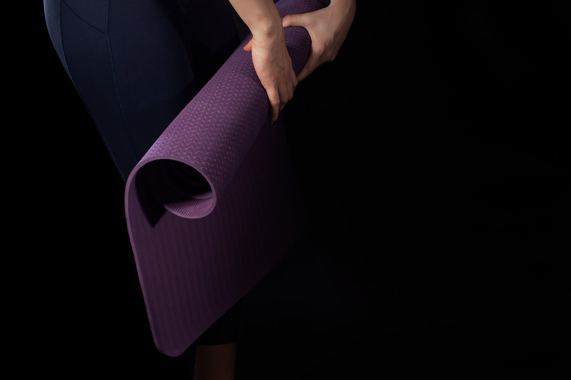 a woman with a purple yoga mat is stretching up