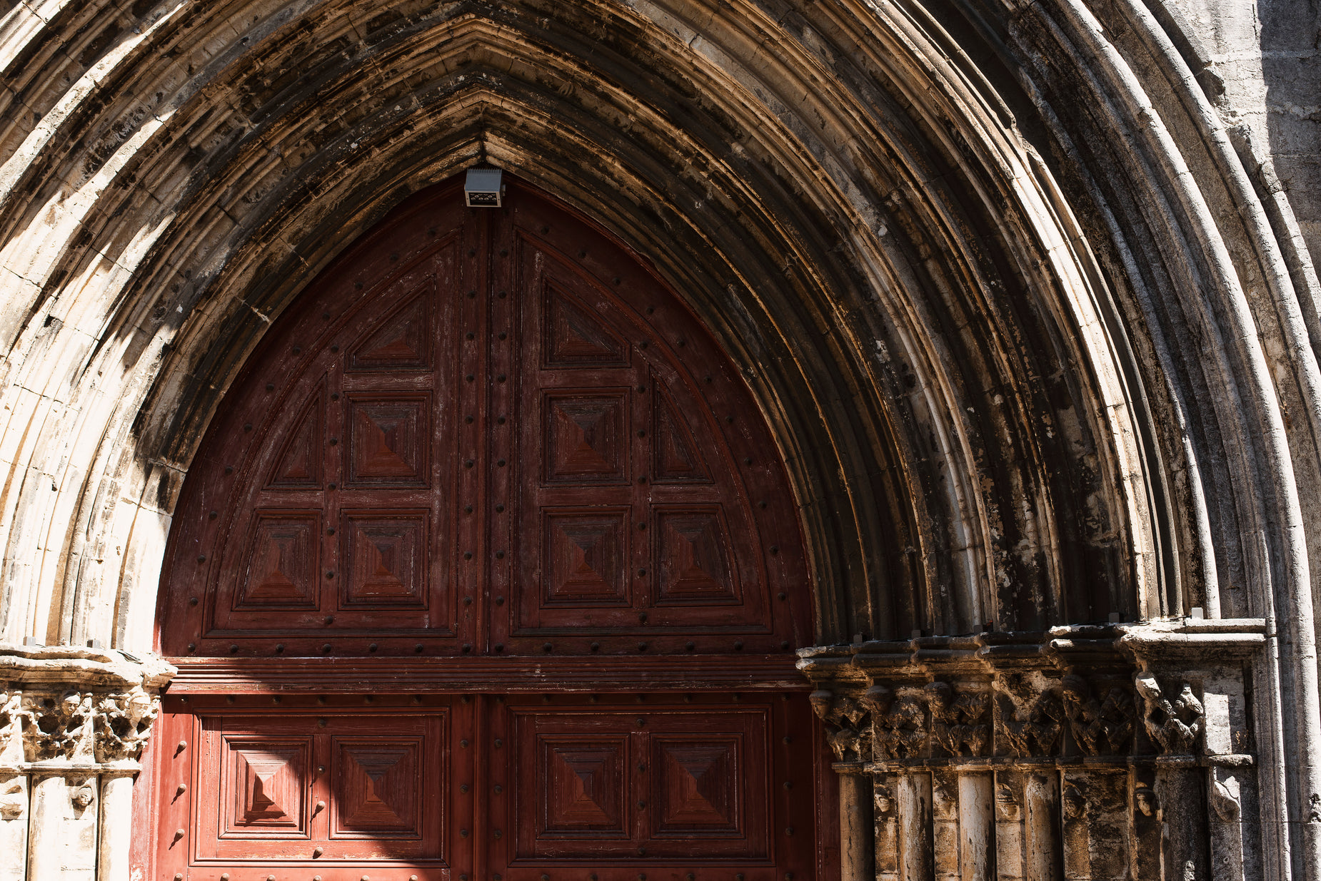 an arched doorway with two stone pillars stands in the sunlight