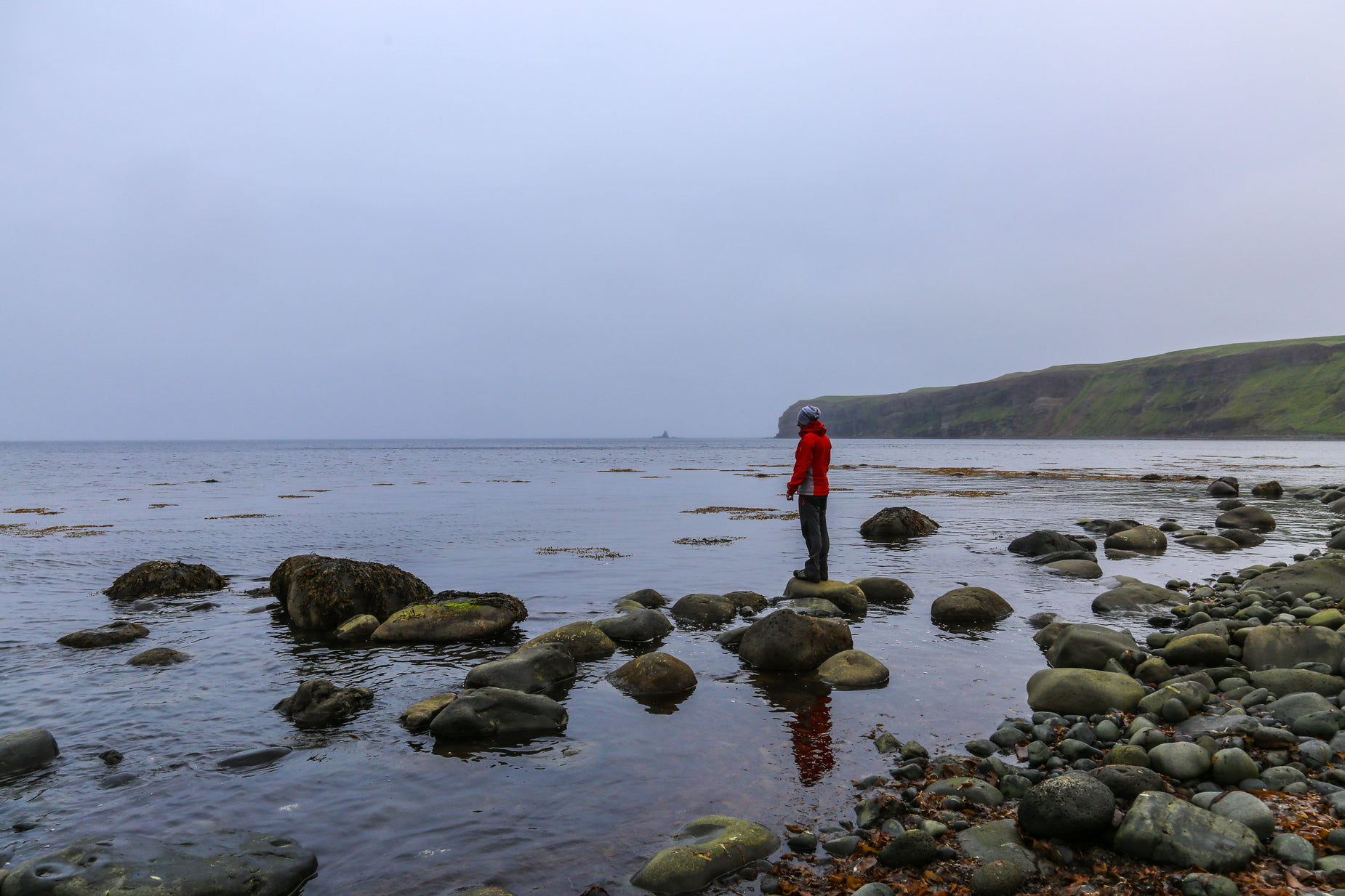 a man stands on some rocks while he looks out into the water