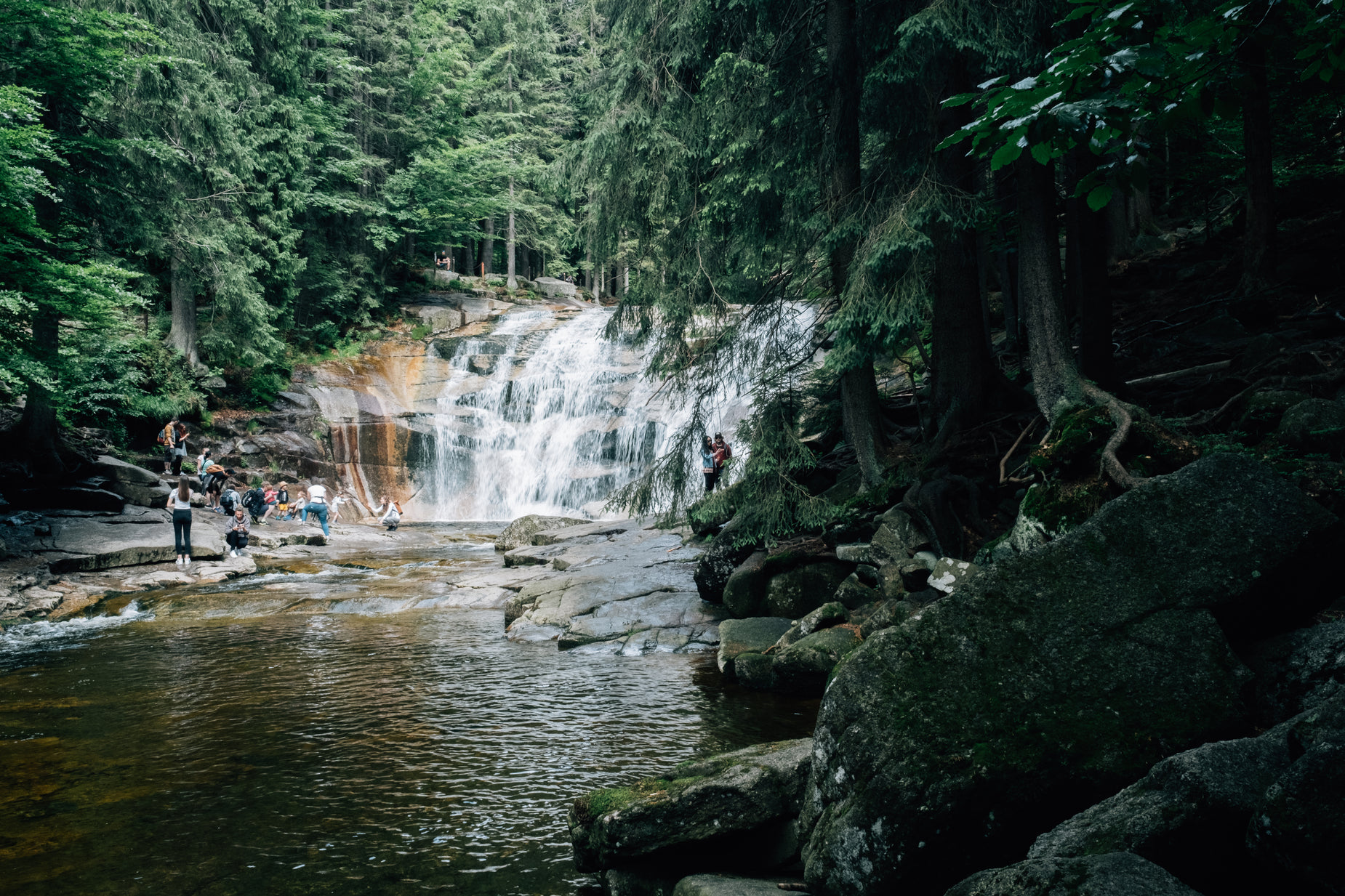 people are sitting by the water at a waterfall