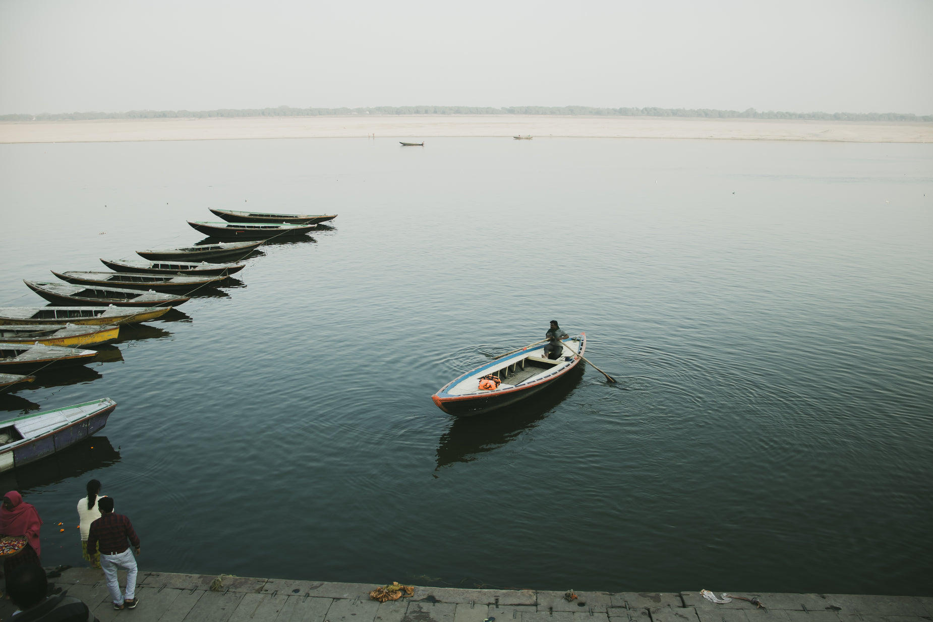 small boat floating next to the shore line with several people