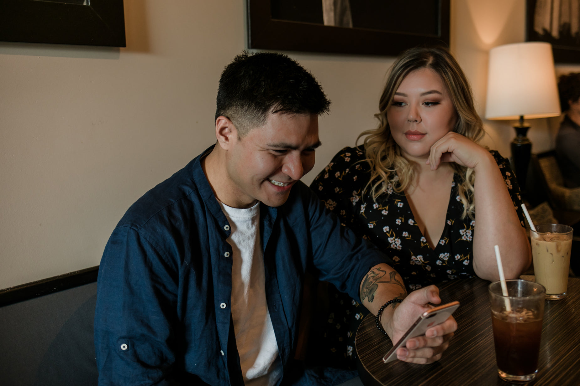 man with tattooed arm looking at his phone next to a woman