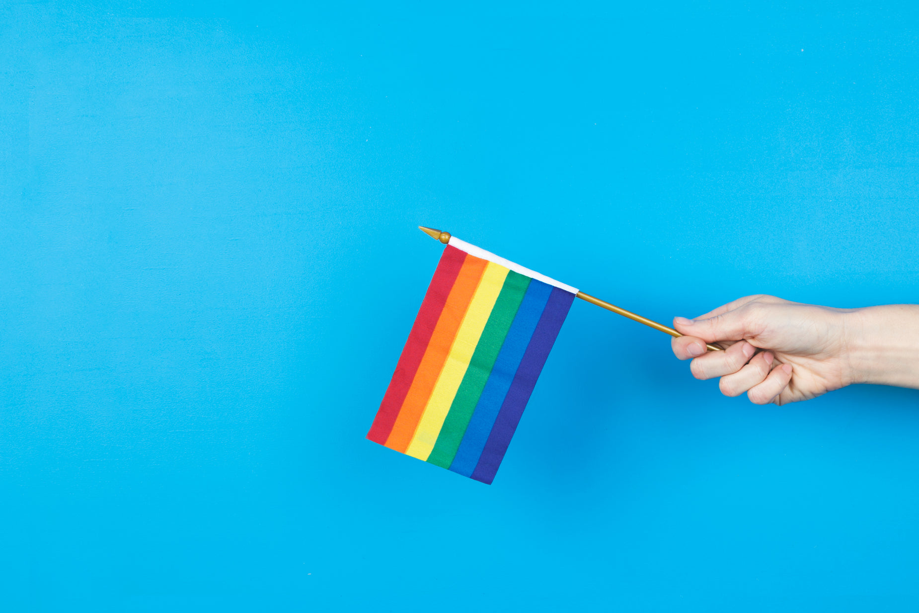 a person holding a rainbow pin and holding it in the air
