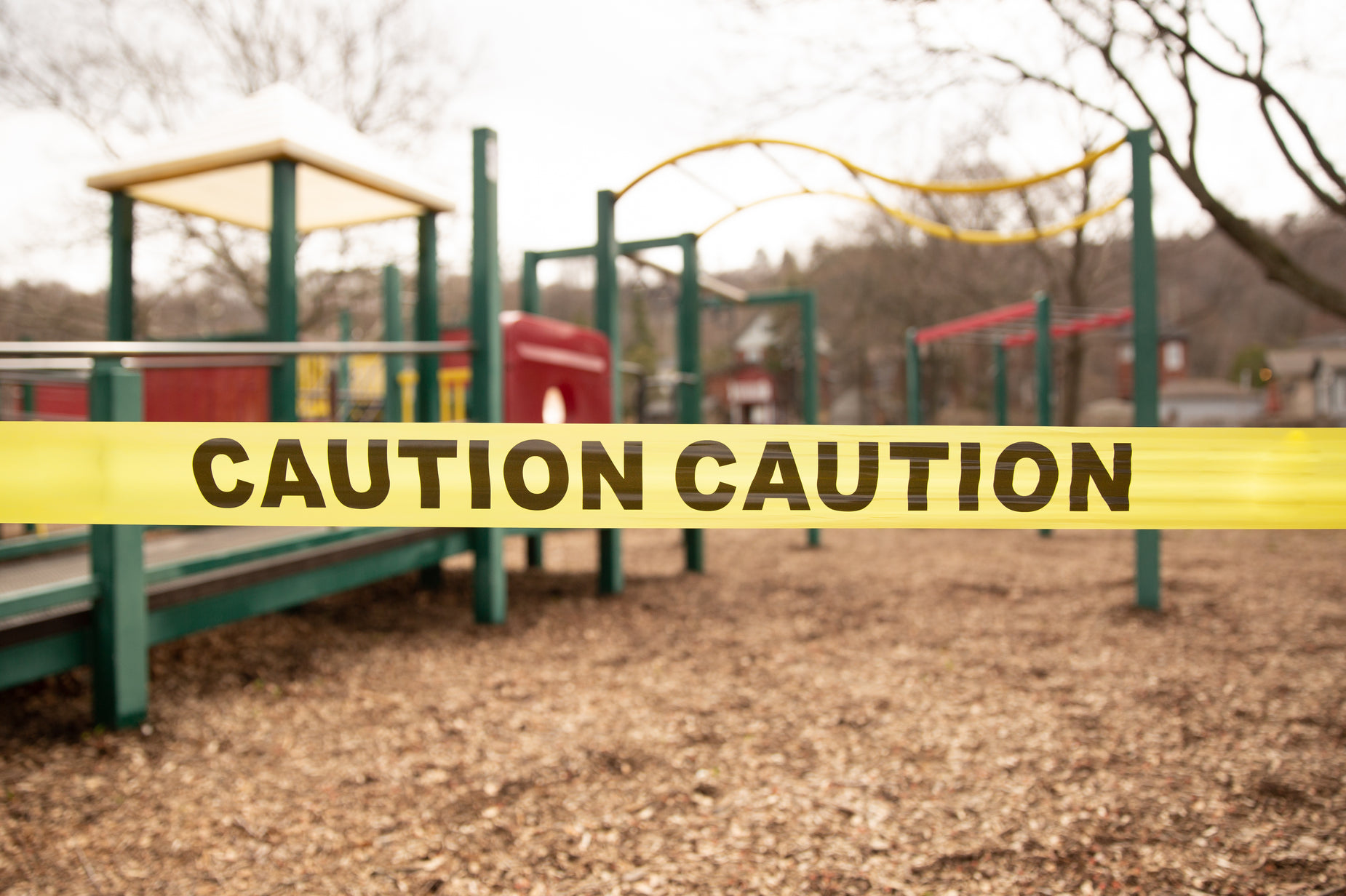 a caution tape sits on the ground near some playground equipment