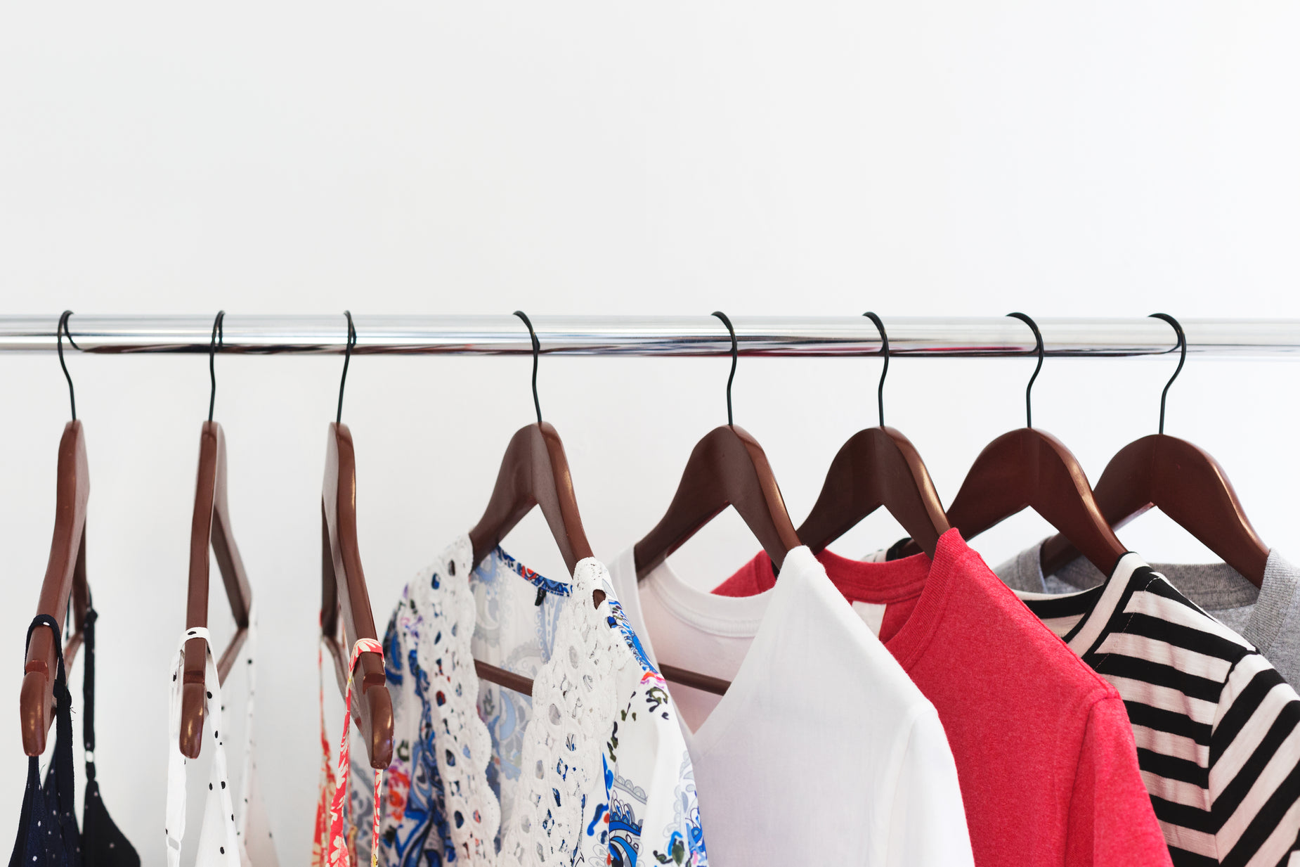 several women's shirts hung on hooks in a closet