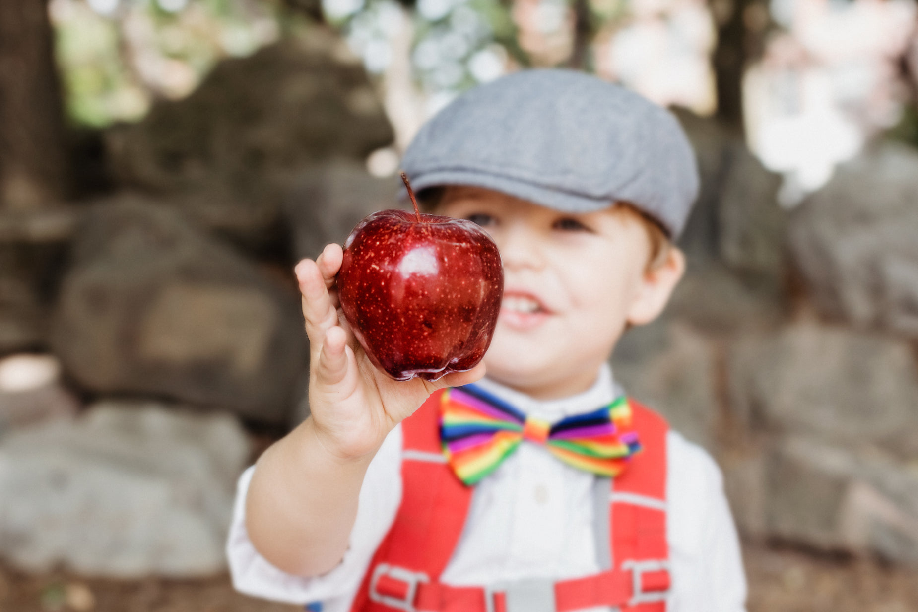 the little boy is holding up an apple