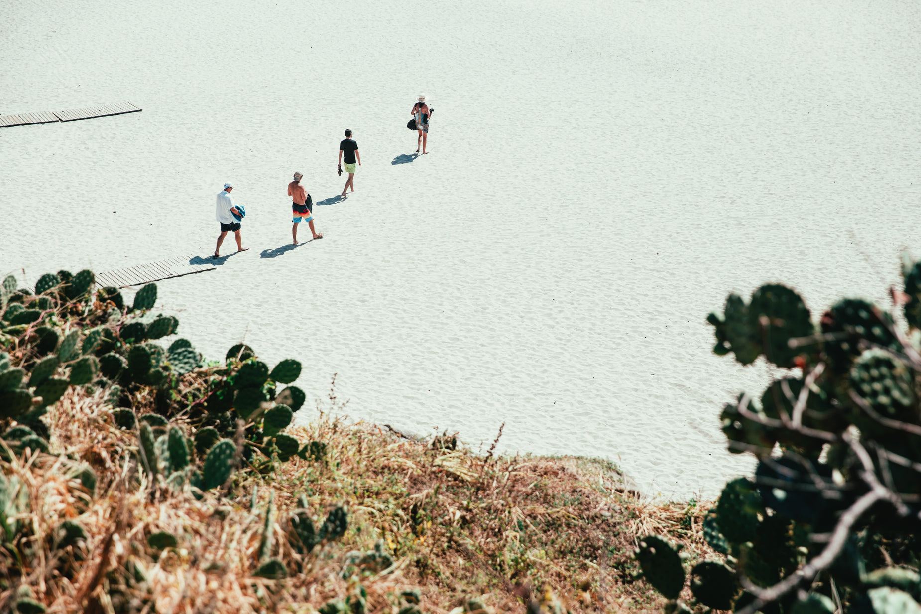 people are walking on the sand towards the ocean