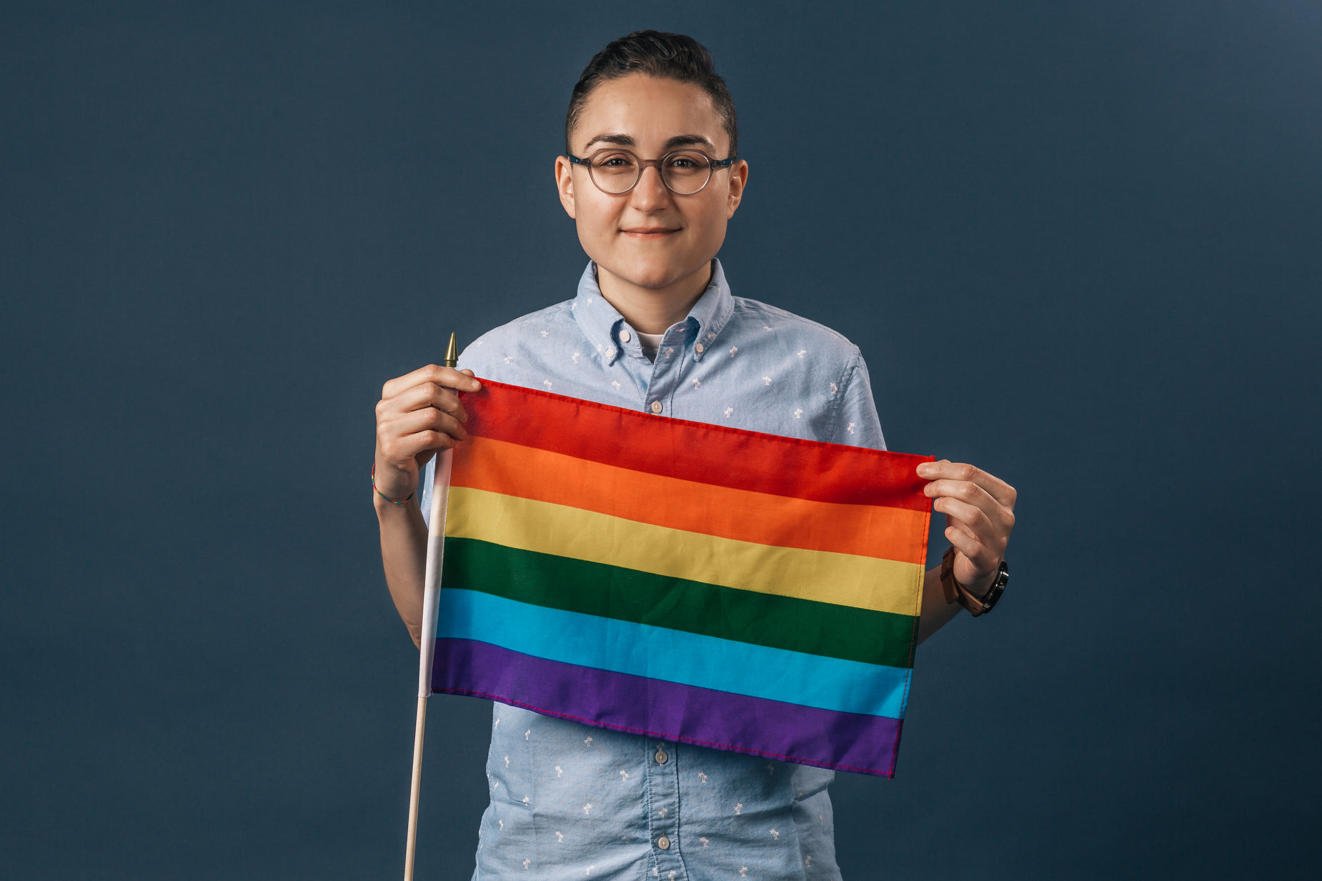 a person holding a rainbow flag in front of their face