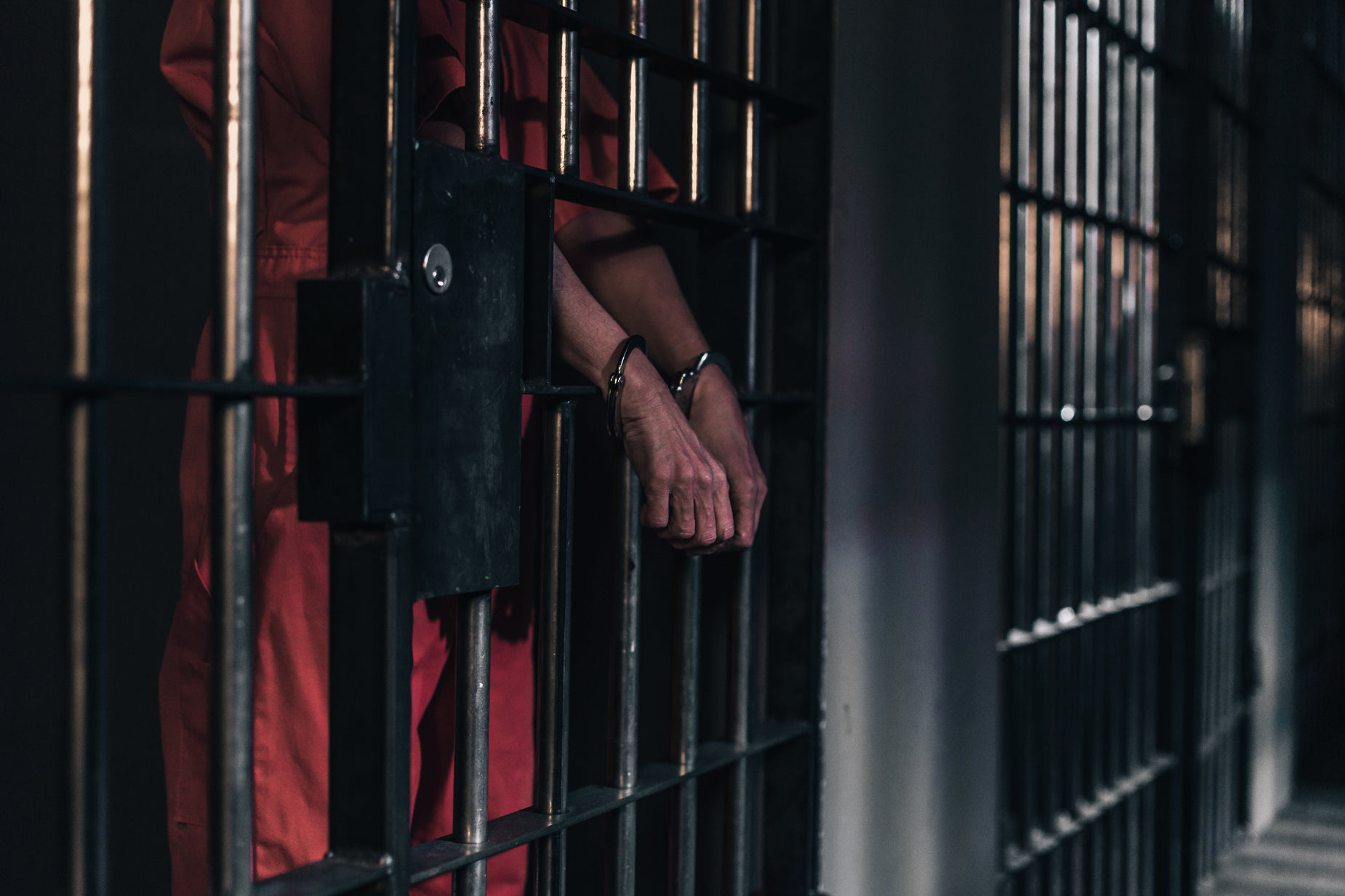 person in red outfit leaning out of cell door
